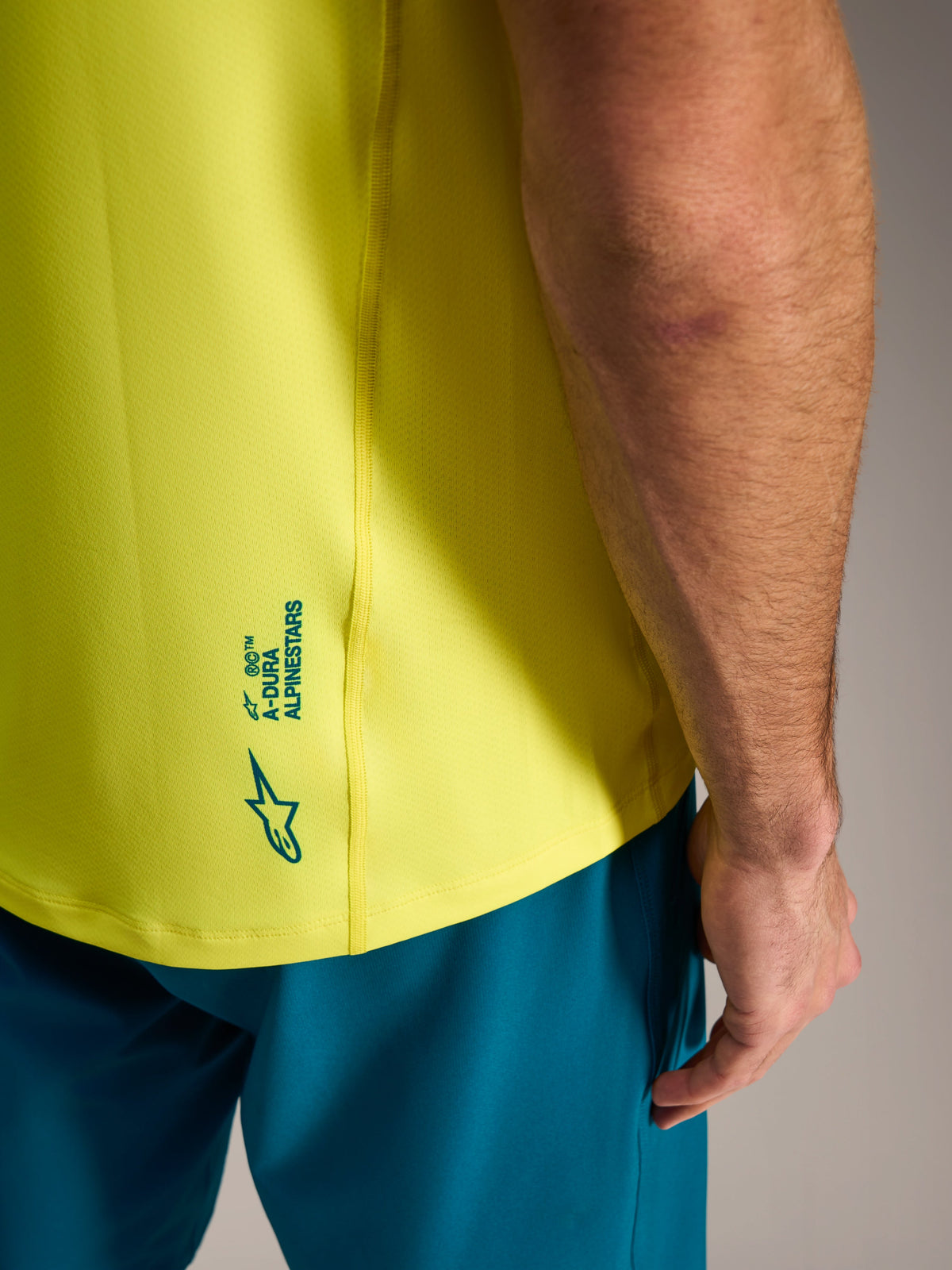 Neon-gelbes A-Dura Ride Trikot mit Alpinestars Logo-Details am unteren Rücken, leichte MTB-Bekleidung.