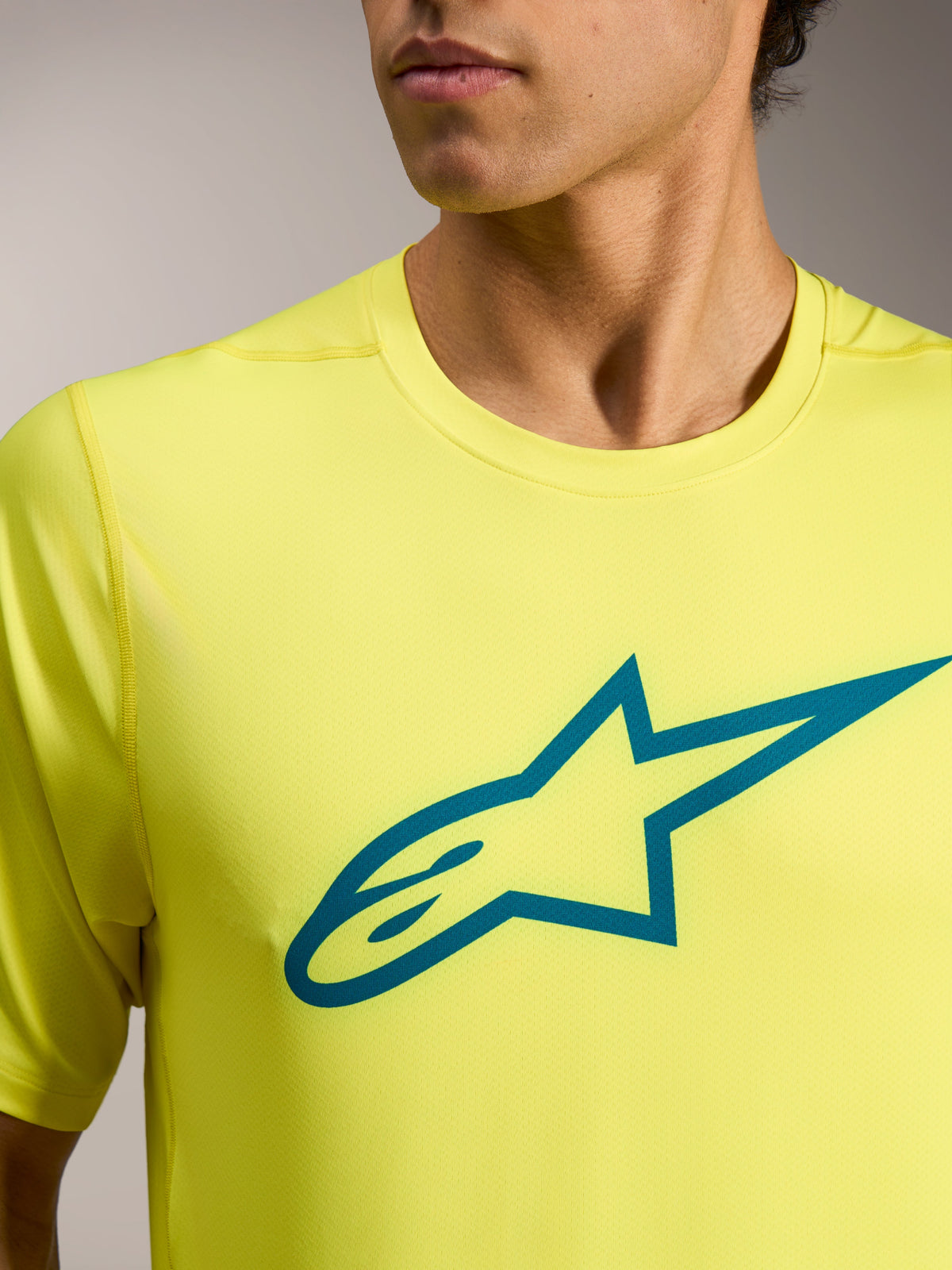 Gelb fluoreszierendes A-Dura Ride Kurzarmtrikot mit blaugrünem Astars-Logo auf der Brust, technische MTB-Bekleidung.