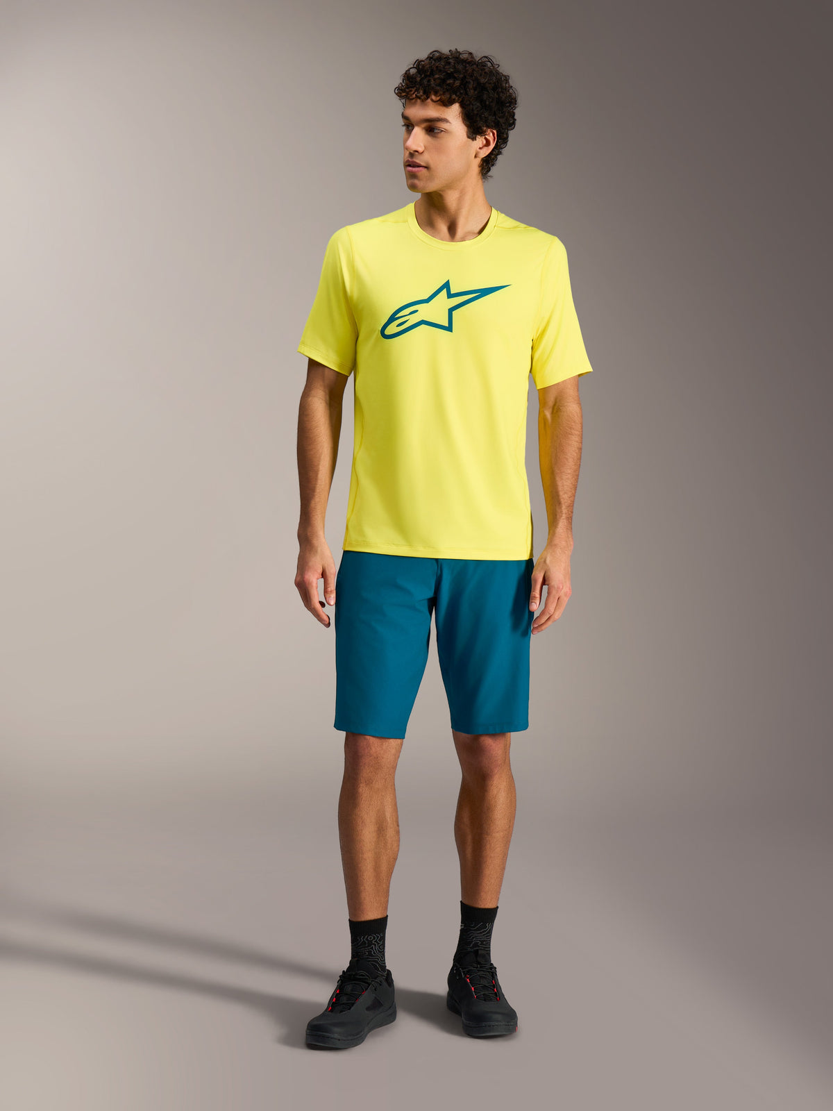 Gelbes Fluo A-Dura Ride Kurzarmtrikot mit türkisfarbenem Astars-Logo, technische MTB-Performance-Bekleidung für Herren.