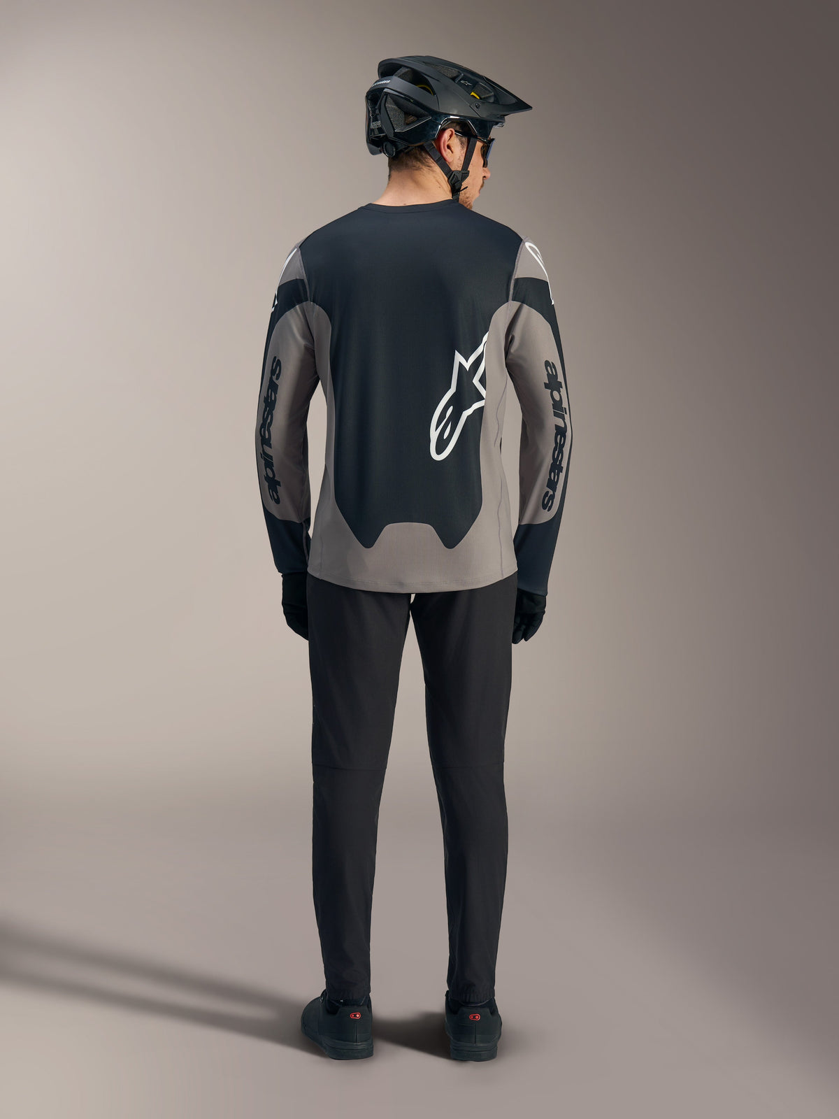 Graues A-Dura Race Langarmtrikot, Rückansicht mit schwarzen Einsätzen und weißen Alpinestars-Logos für MTB-Fahrten.