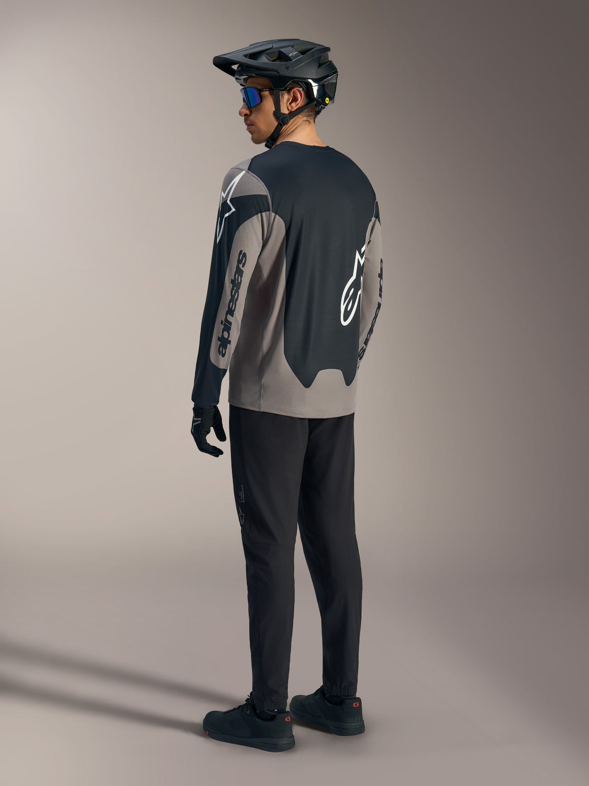 Grau-schwarzes A-Dura Race Langarmtrikot von Alpinestars, Rückansicht in kompletter Mountainbike-Ausrüstung.