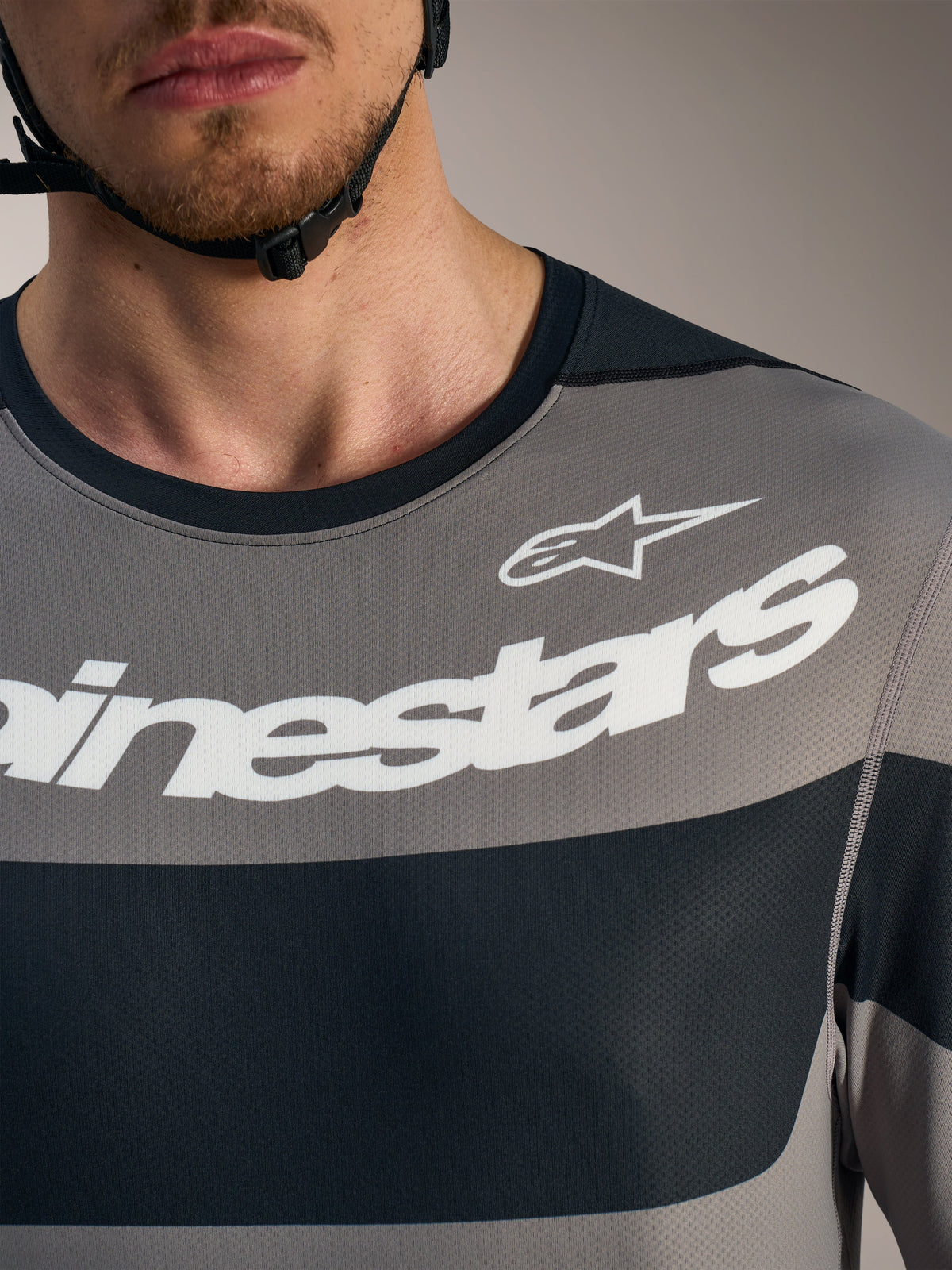 Graues A-Dura Race Langarmtrikot, Brustdetail mit weißen Alpinestars-Logos und atmungsaktivem Mesh-Gewebe.
