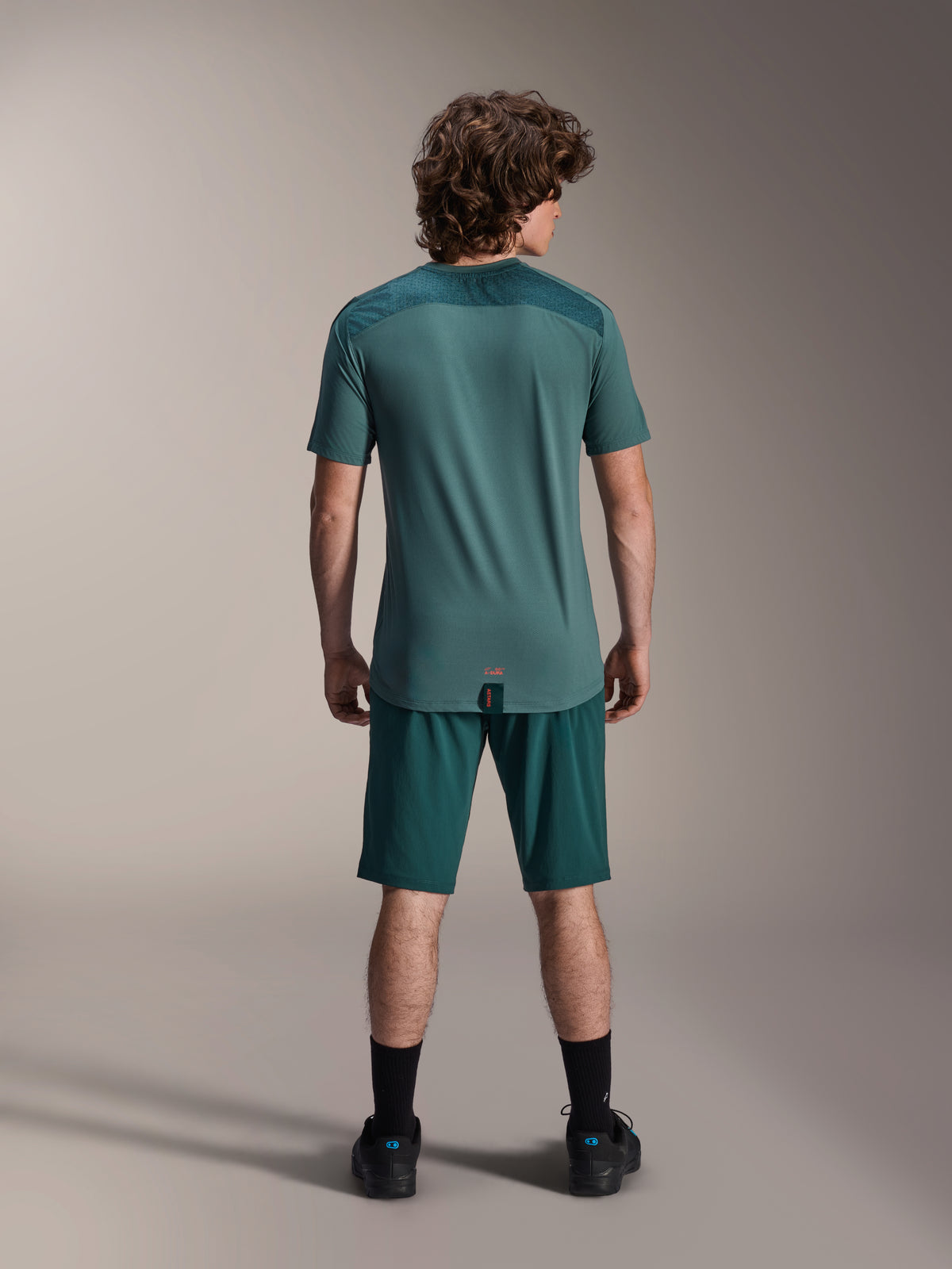 Alpinestars A-Dura Shorts und A-Dura Lipan SS Jersey, Dark Pine Grün, Rückansicht an einem Modell, Performance-Mountainbike-Bekleidung bestehend aus Kurzarmtrikot und passenden Shorts, Offroad-Radsport-Outfit