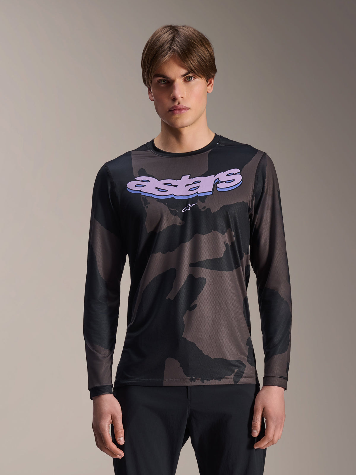 Alpinestars A-Dura Hollow Camo Langarmtrikot, MTB-Mountainbike-Trikot, schwarz-graues Camouflage-Muster, lila „astars“-Grafik auf der Brust, getragen von einem Model mit schwarzer Hose, lässiges Performance-Design