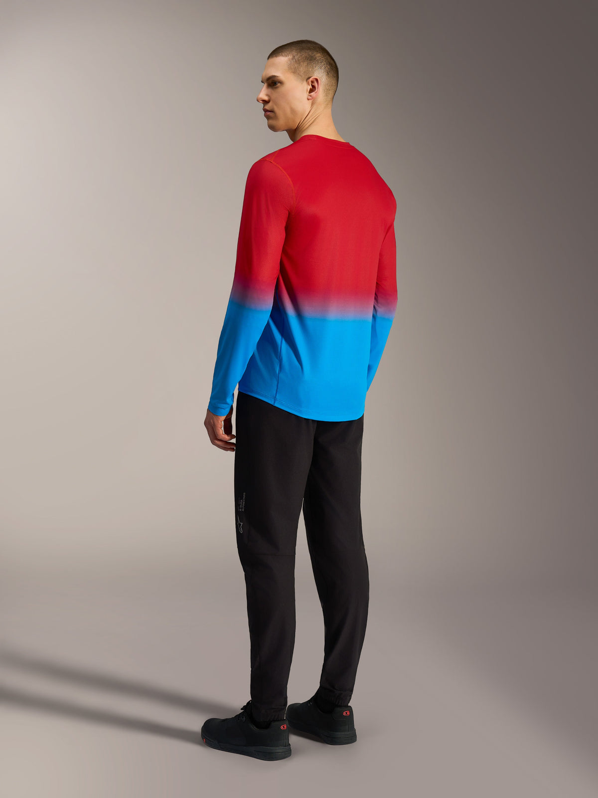 Alpinestars A-Dura ASTARS 2.0 Langarm-MTB-Trikot, rot-blauer Farbverlauf, Rückansicht am Modell in schwarzer Hose.