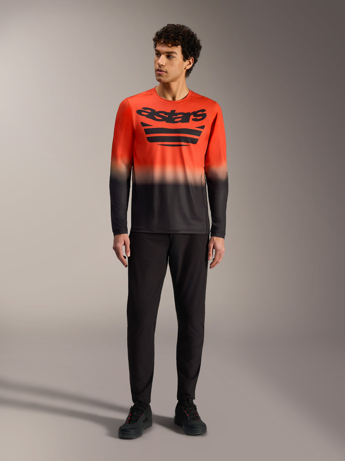 A-Dura ASTARS Langarmtrikot 2.0 mit orange-schwarzem Farbverlauf, großem Brustlogo und schwarzer MTB-Hose.