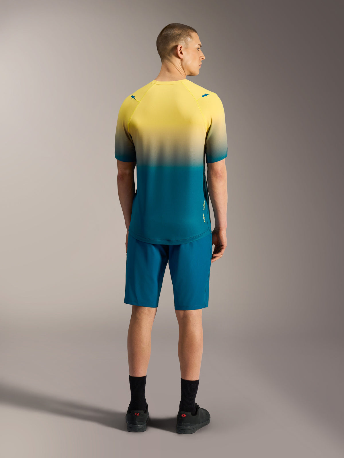A-Dura ASTARS Jersey 2.0, Kurzarm-MTB-Top mit gelb-blaugrünem Farbverlauf, Rückansicht an einem Modell.