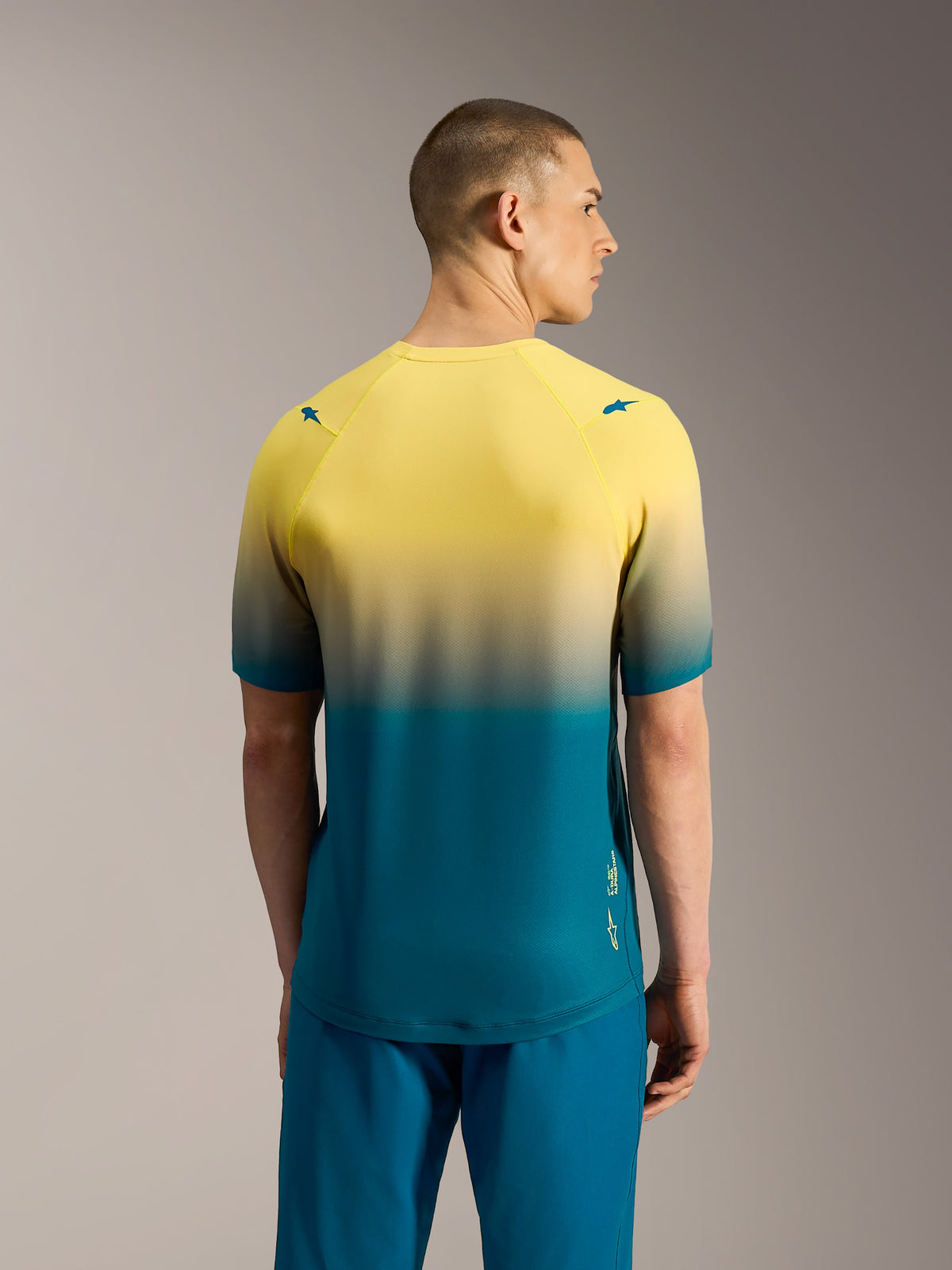 Alpinestars A-Dura ASTARS 2.0 MTB-Kurzarmtrikot, gelb-blaugrüner Farbverlauf, Performance-Radtop in der Rückansicht.
