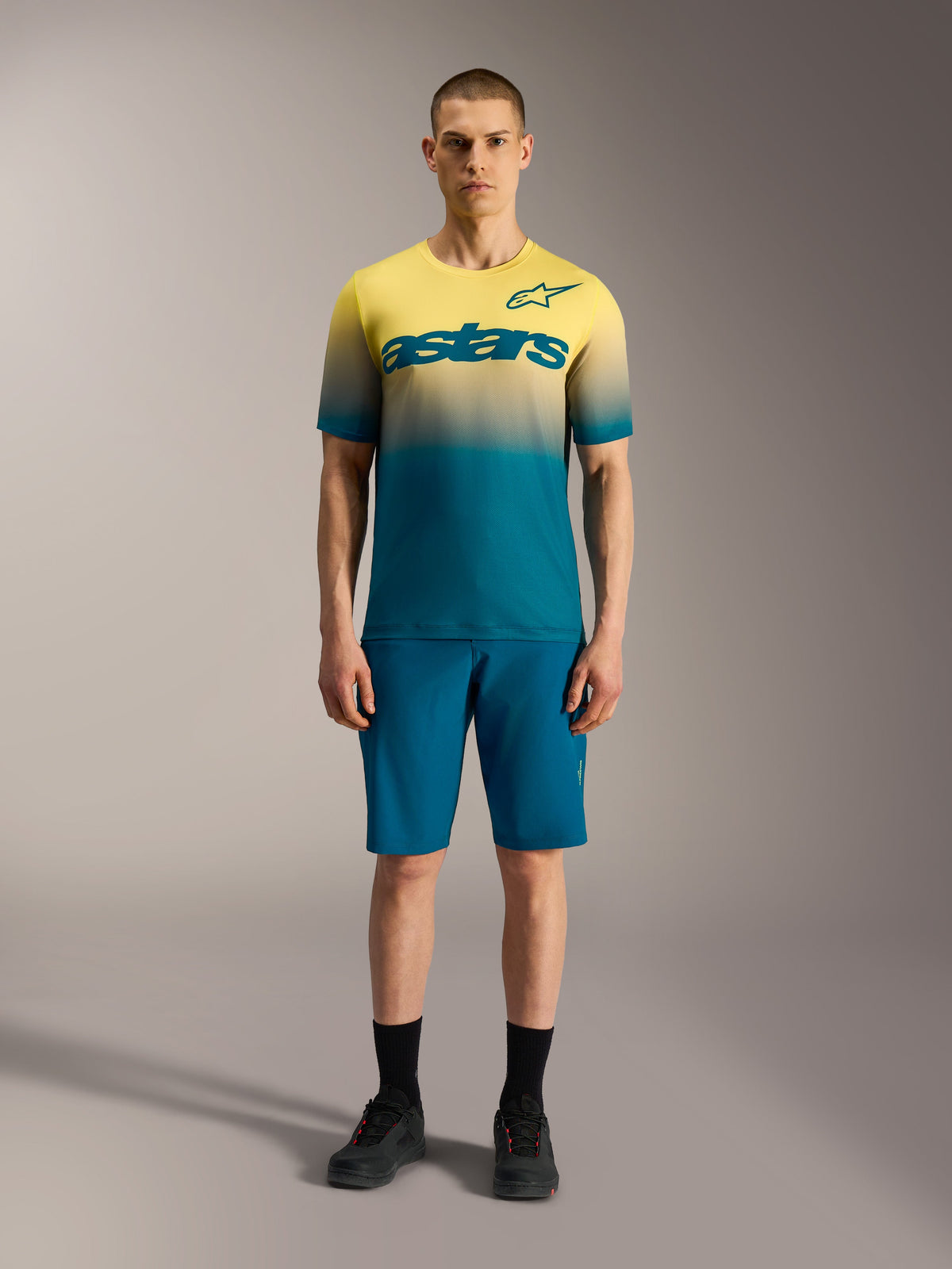 A-Dura ASTARS 2.0 Jersey, Kurzarm-MTB-Oberteil mit gelb-blauem Farbverlauf und markantem Alpinestars-Brustlogo.