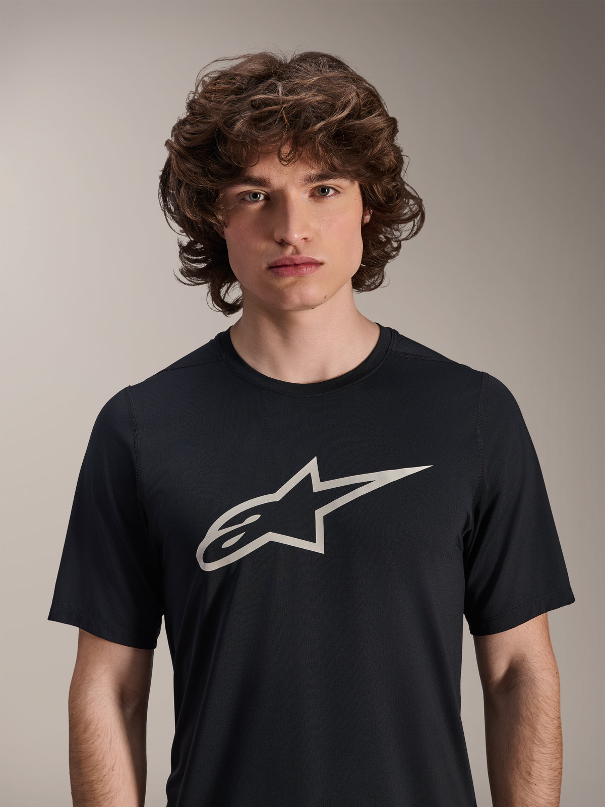 Alpinestars A-Dura Astar Kurzarm-Trikot, Schwarz, mit großem weißem Astar-Logo auf der Brust, getragen von einem männlichen Model, lässige Mountainbike-Performance-Bekleidung