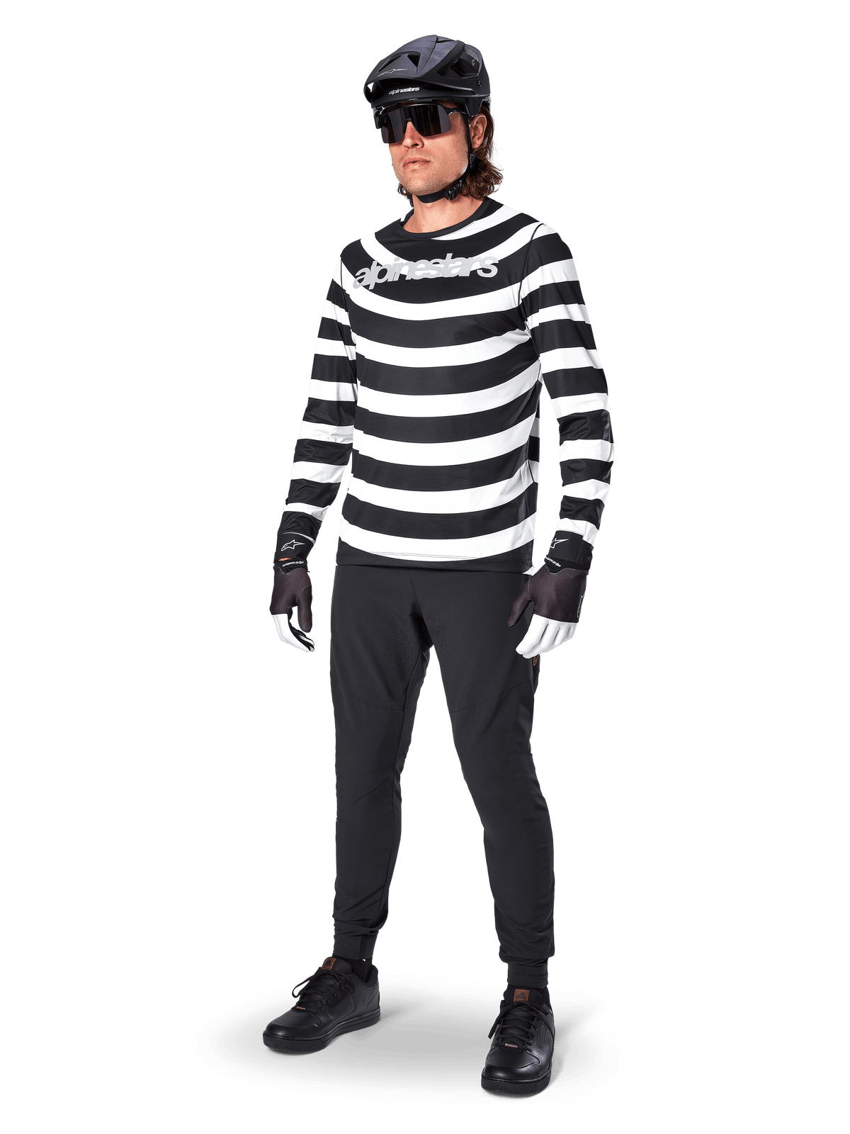 Alpinestars A-Aria Oscar Langarmtrikot, Schwarz und Weiß mit markanten horizontalen Spiralstreifen, weißes geschwungenes Alpinestars-Logo, Performance-MTB-Bekleidung getragen mit schwarzer Radhose und Helm