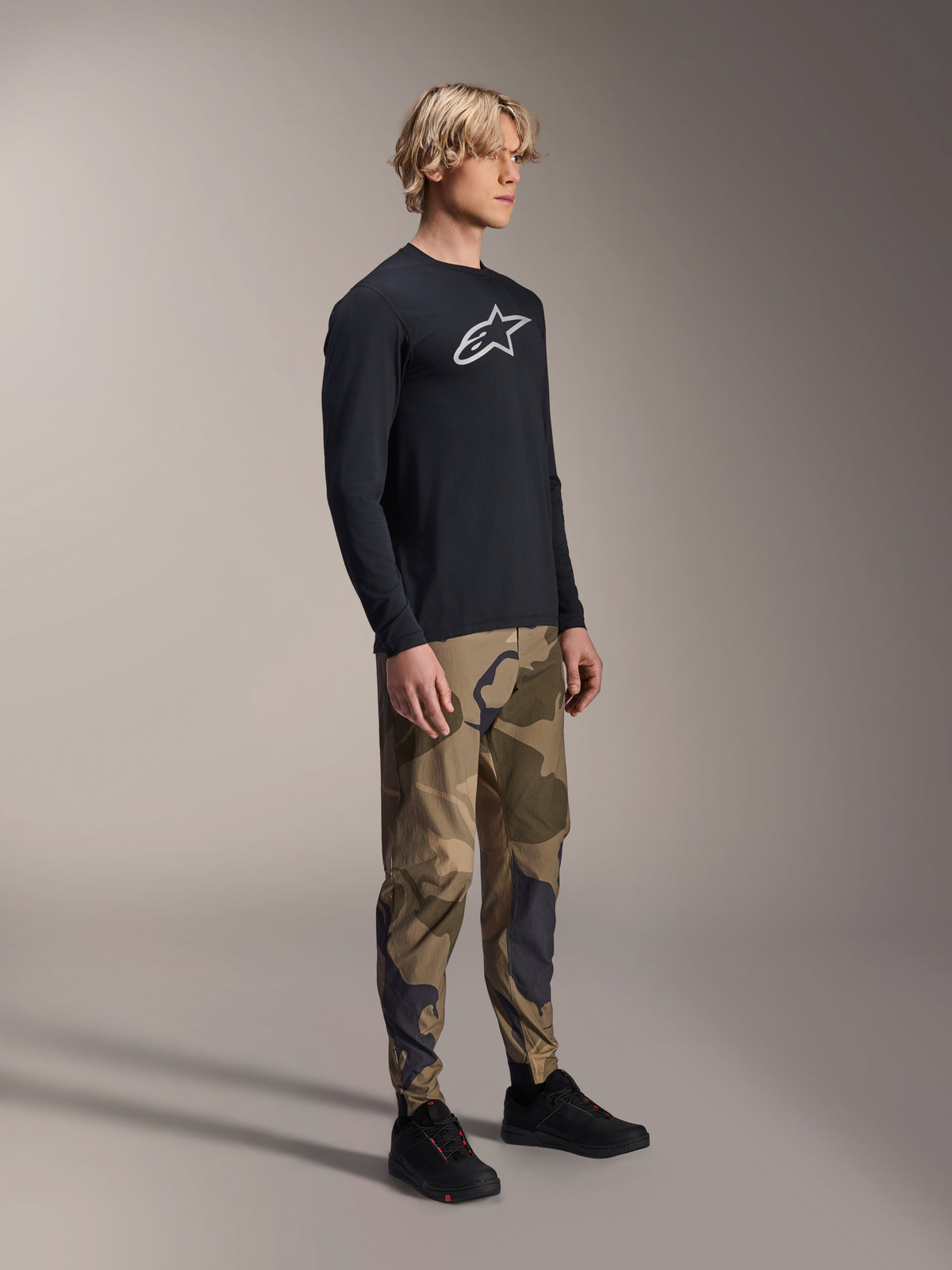 Alpinestars A-Dura Camo Pant, MTB Pants, Brown Camouflage, worn with a black A-Dura Astar Long Sleeve Jersey and black shoes, technical mountain bike apparel for trail riding.