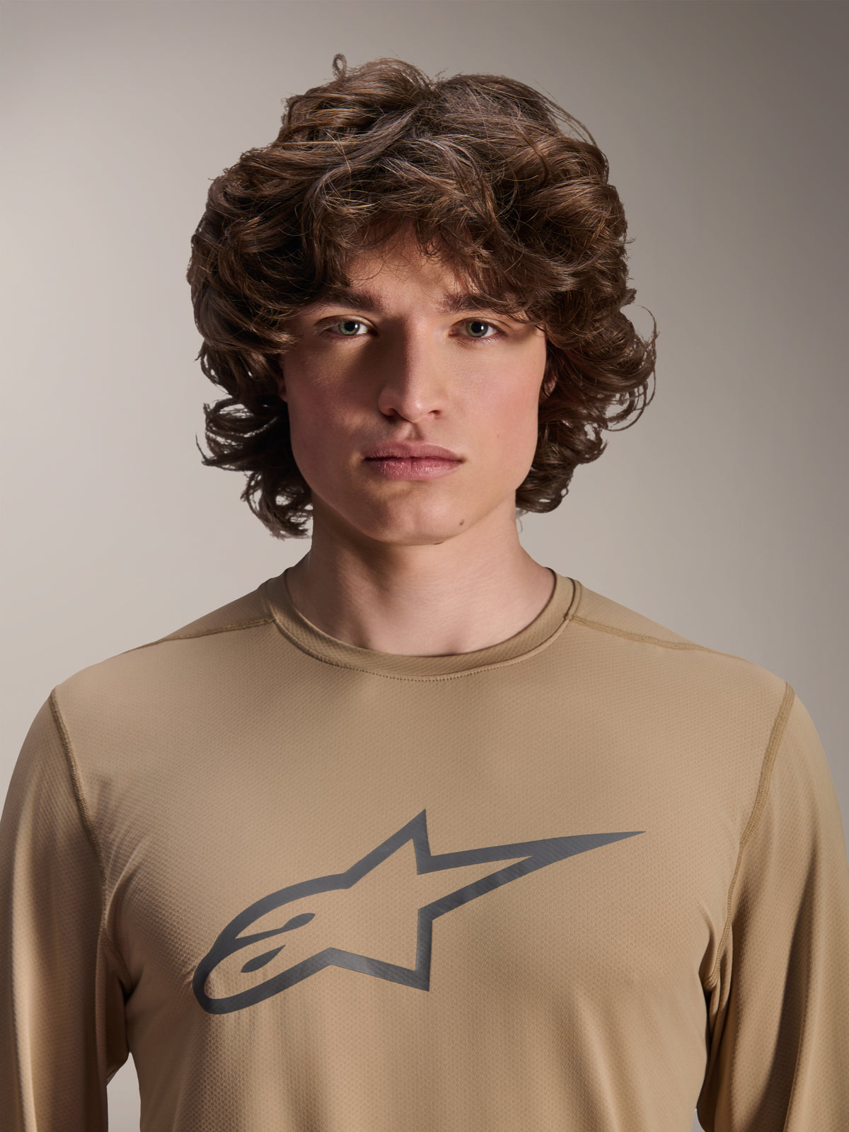 Alpinestars A-Dura Astar Long Sleeve Jersey, Light Brown, worn by male model, featuring a large Astars logo on the chest, jacquard fabric texture, casual mountain bike apparel