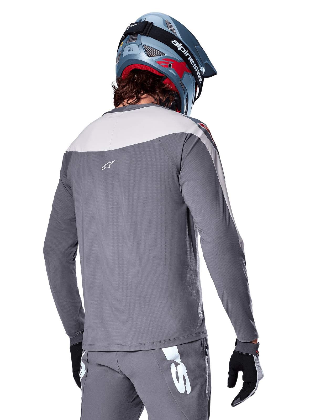 Alpinestars A-Supra Race Jersey, Long Sleeve MTB Jersey in Dark Gray and light gray, back view showing performance fit and Astar logo, worn with matching gray pants and a blue mountain bike helmet, engineered for off-road mountain biking.