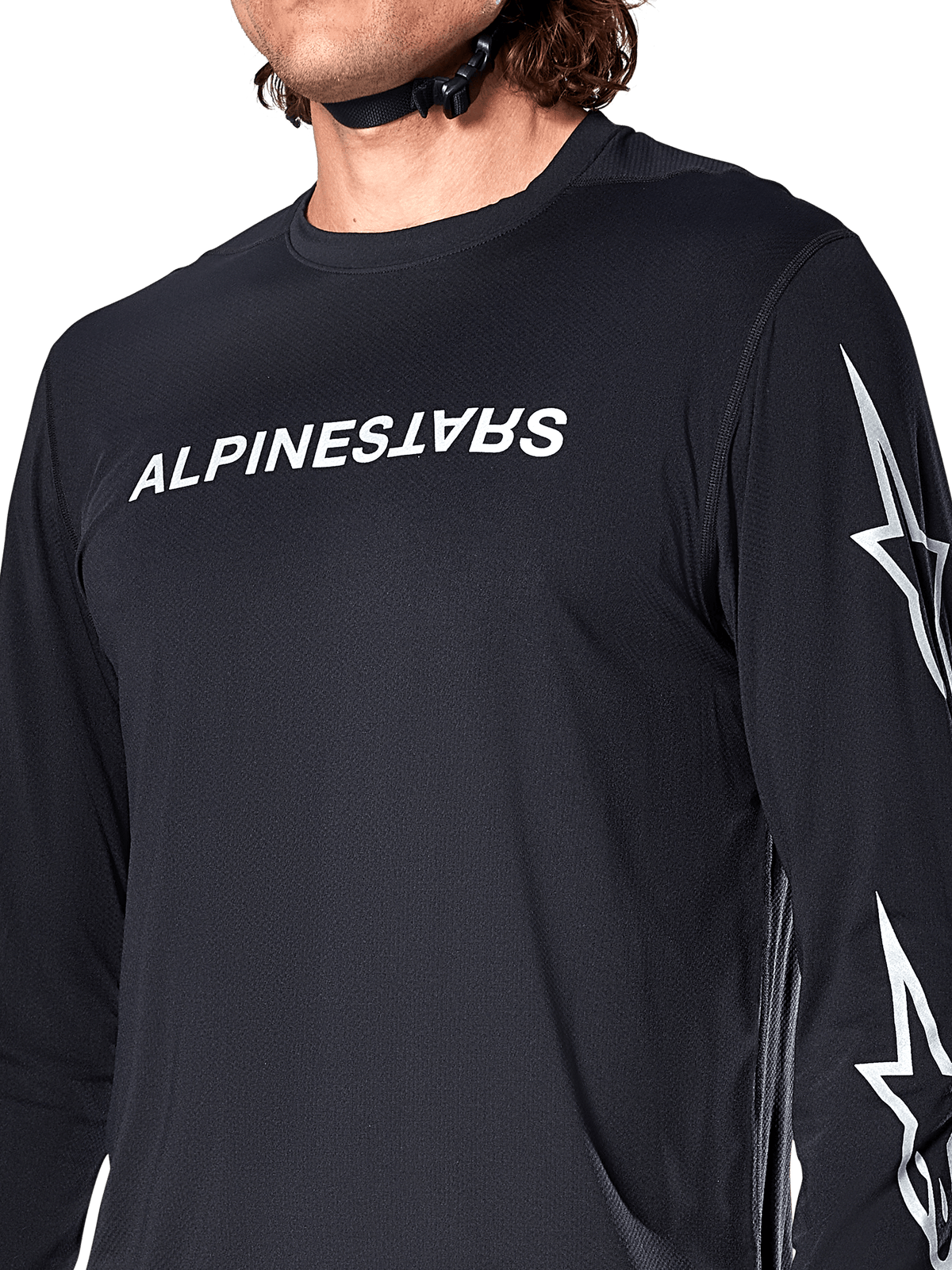 Alpinestars A-Dura Switch Long Sleeve Jersey, Black, featuring white Alpinestars wordmark on the chest and star logos on the sleeve, worn by a rider with a helmet strap visible, technical mountain bike apparel.