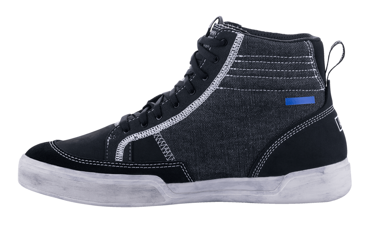 Alpinestars Ageless Riding Shoes, Motorradschuhe in Schwarz und Cool Gray, Seitenansicht, Konstruktion aus Canvas und Wildleder mit weißen Kontrastnähten, High-Top-Sneaker-Stil mit off-white Sohle und schwarzen Schnürsenkeln.