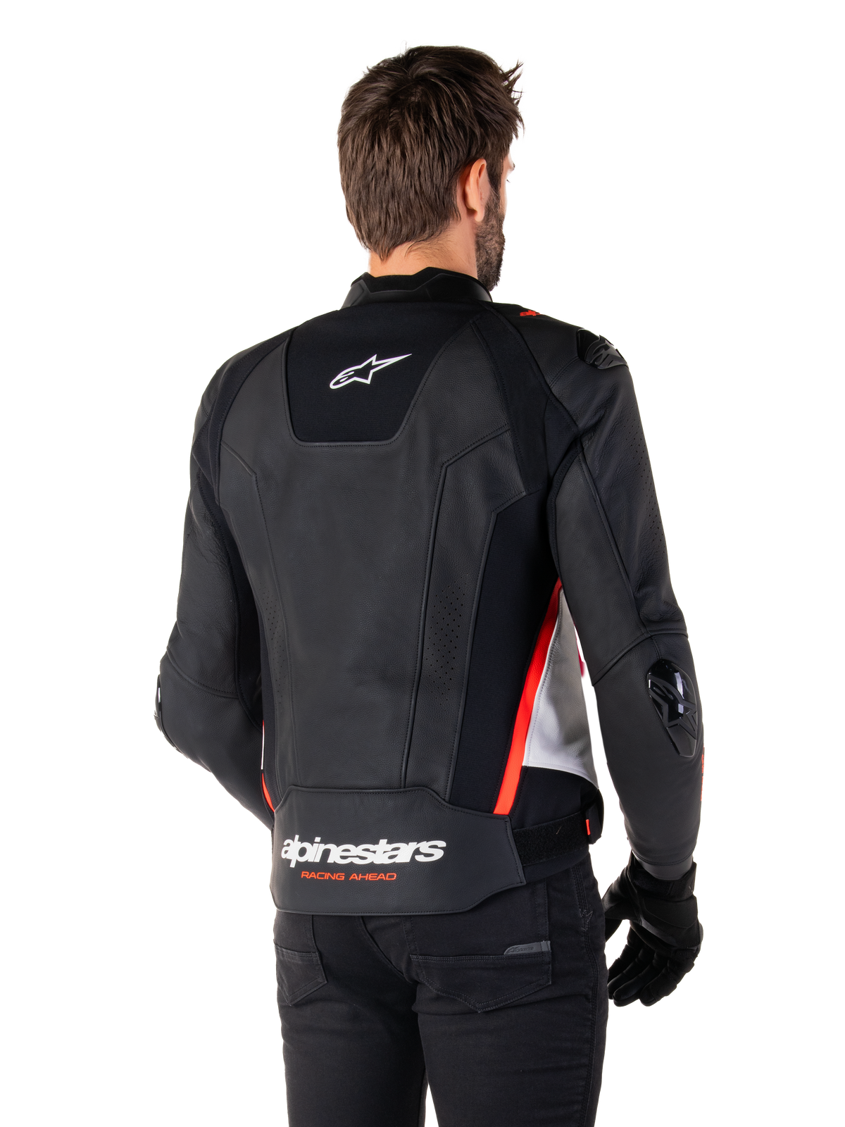 Alpinestars Missile V3 Lederjacke, Rückansicht an einem Fahrer, Schwarz, Weiß und Fluo-Rot, mit markantem Alpinestars-Branding und „RACING AHEAD“-Schriftzug am unteren Rücken, hochwertige Lederkonstruktion mit technischen Stretch-Einsätzen und schützenden TPU-Schleifern, getragen mit schwarzen Handschuhen und einer schwarzen Hose.