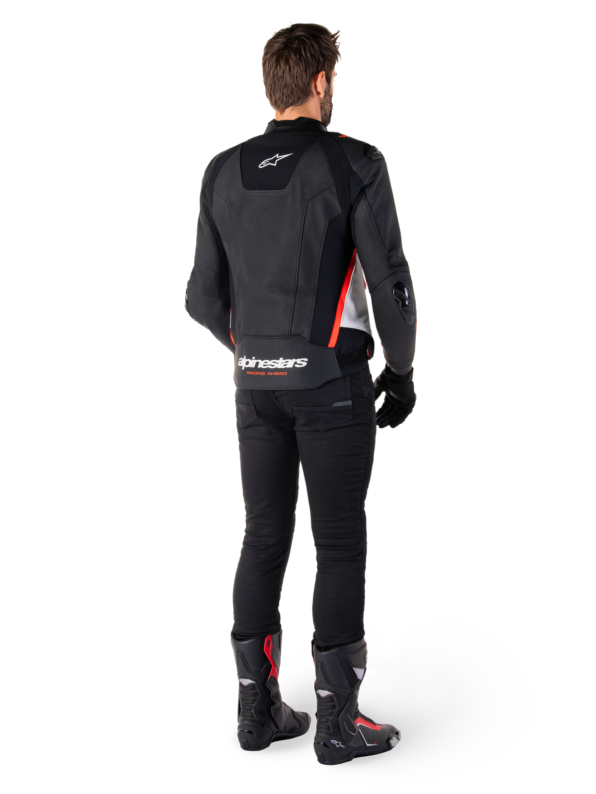 Alpinestars Missile V3 Lederjacke in Schwarz Weiß Rot Fluo, Rückansicht eines männlichen Fahrers, mit Alpinestars-Branding auf dem oberen und unteren Rücken, kombiniert mit einer schwarzen Hose und Motorradstiefeln, rennsportinspirierte Leder-Sportjacke.