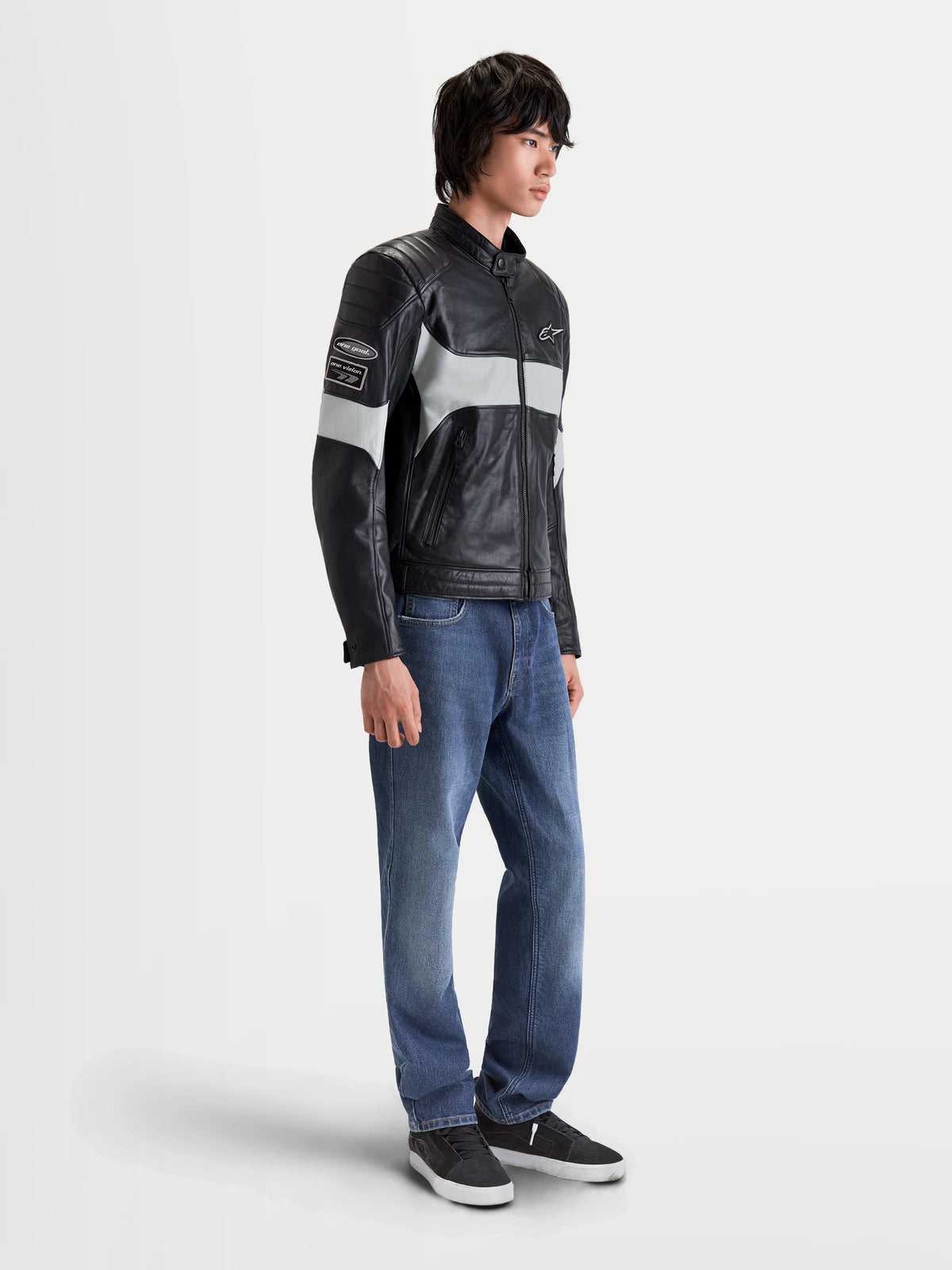Alpinestars Revern Leather Jacket, men's urban motorcycle leather jacket in black and metal gray, side profile view worn by a model with jeans, featuring distressed full-grain leather construction and heritage styling.