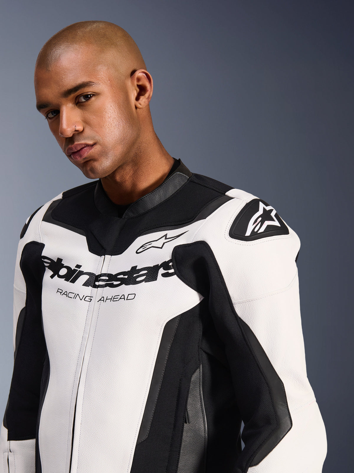 Alpinestars GP Force V2 Leather Jacket, White and Black, worn by a male model, features premium bovine leather construction, black stretch panels, Alpinestars logo and 'Racing Ahead' text on the chest, and protective shoulder shields.