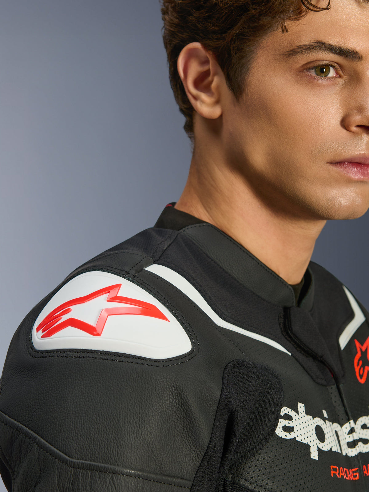 Alpinestars GP Force V2 Air Lederjacke, Schwarz und Weiß, Nahaufnahme eines Models, das die Jacke trägt, mit weißem GP Lite Evo DFS Schulterschleifer mit rotem Logo und perforiertem Lederdetail.
