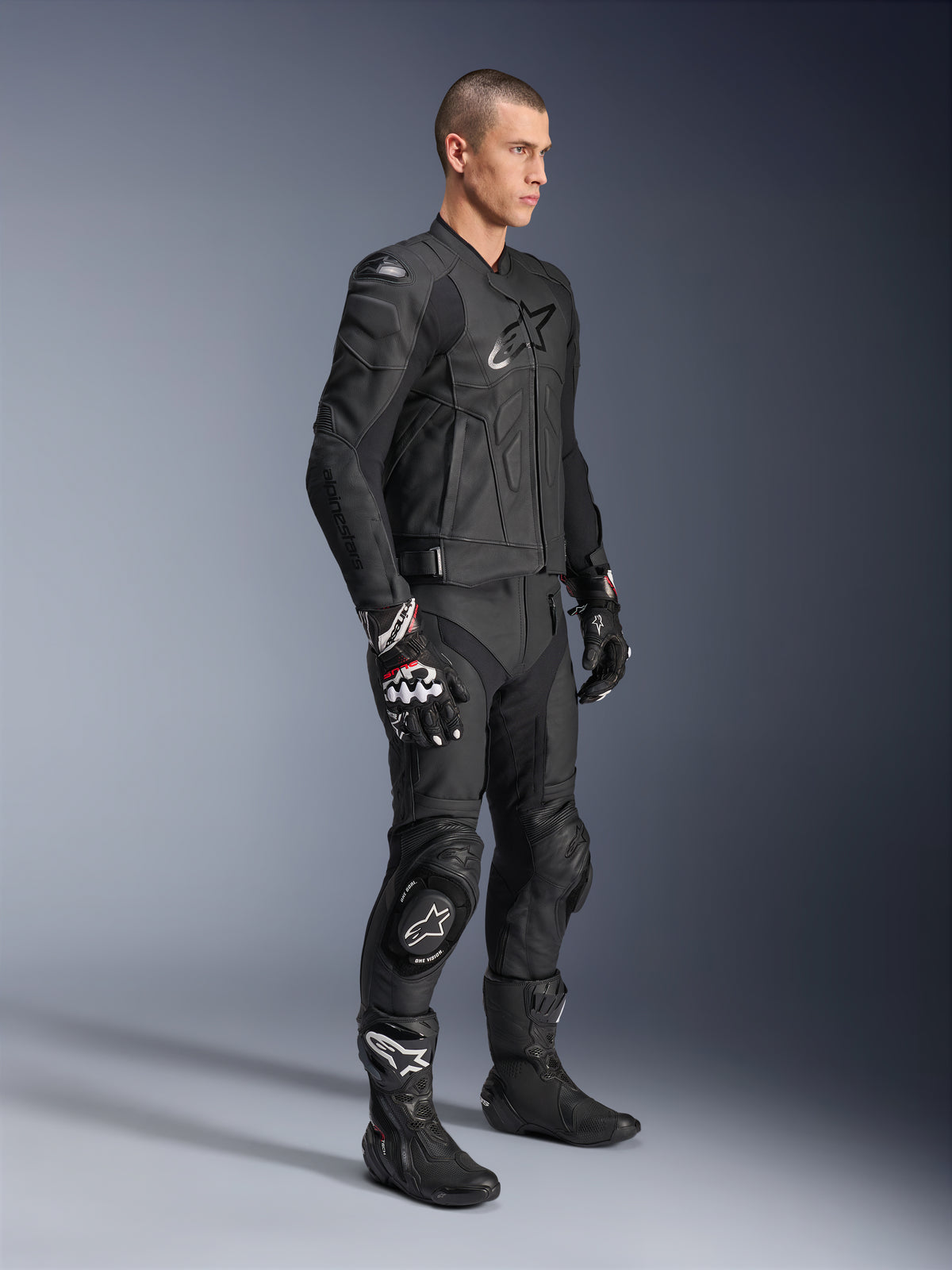 Alpinestars Missile V3 Lederhose, kombiniert mit einer passenden schwarzen Lederjacke, Handschuhen und Stiefeln, mit Knieschleifern und sportlicher Passform, komplett schwarze Motorrad-Schutzausrüstung für Rennstrecke und Straße.