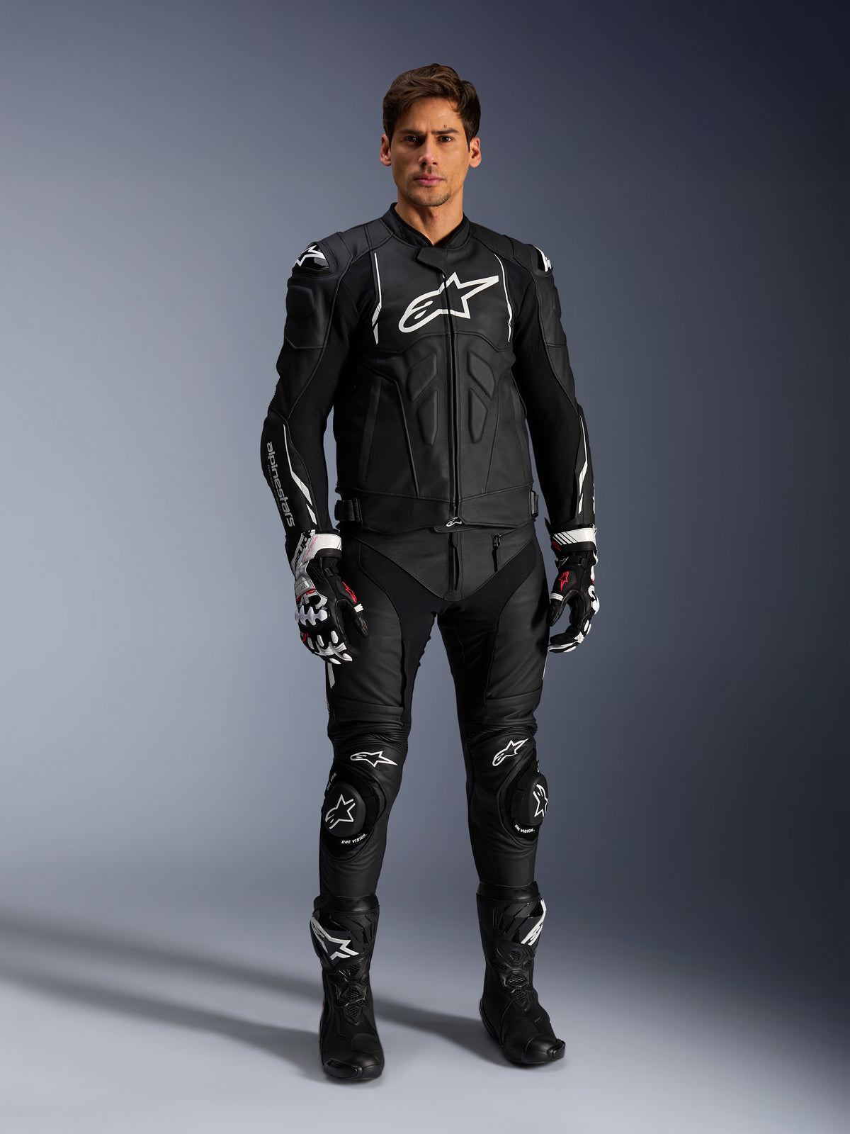 Alpinestars Dusk Lederjacke, Herren-Motorradjacke für Road Racing und Sport, Schwarz und Weiß, aus hochwertigem Rindsleder, getragen von einem Model.