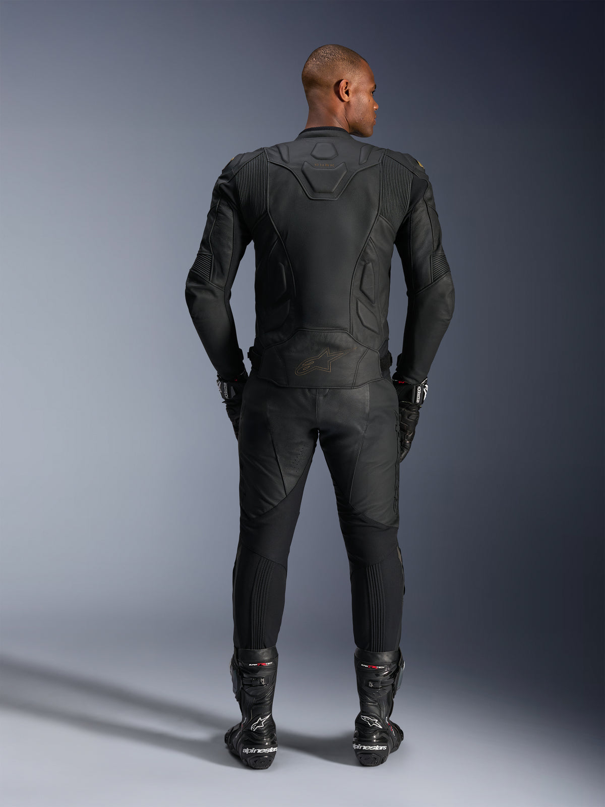 Alpinestars Dusk Lederjacke, Motorrad-Rennjacke, Schwarz, Rindsleder, Rückansicht eines Fahrers in Schutzausrüstung.
