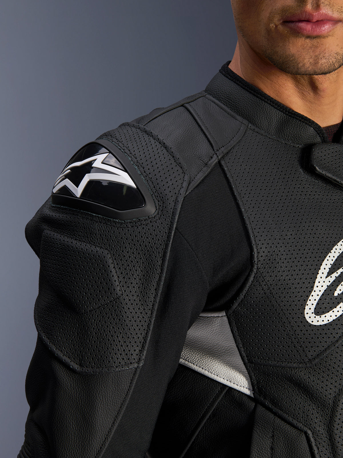 Alpinestars Dusk Airflow Lederjacke, Schwarz und Weiß, Nahaufnahme von Schulter und Brust, mit perforiertem Leder für Belüftung, DFS-Schulterschutz mit weißem Alpinestars-Logo, sportliches Design