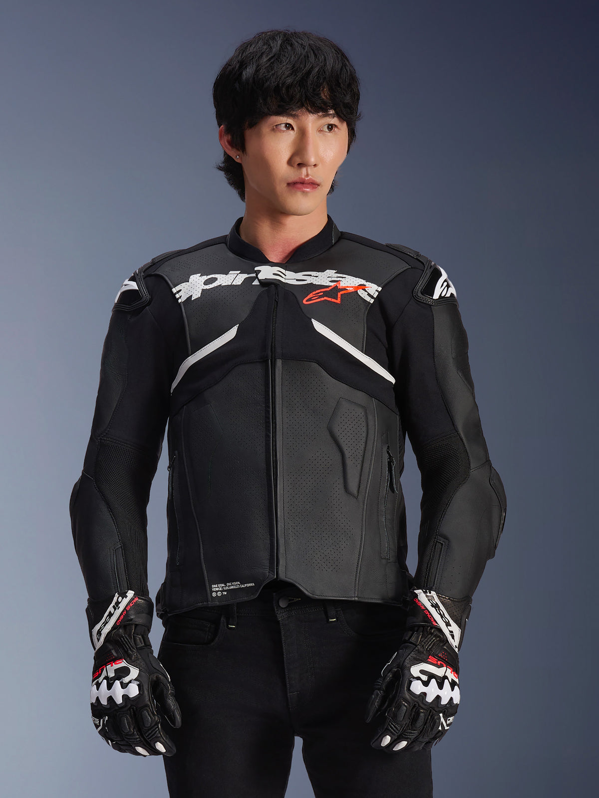 Alpinestars Atem V5 Lederjacke, Motorrad-Rennjacke, Schwarz mit weißen und roten Akzenten, Premium-Lederkonstruktion mit Protektoren, getragen mit passenden Racing-Handschuhen