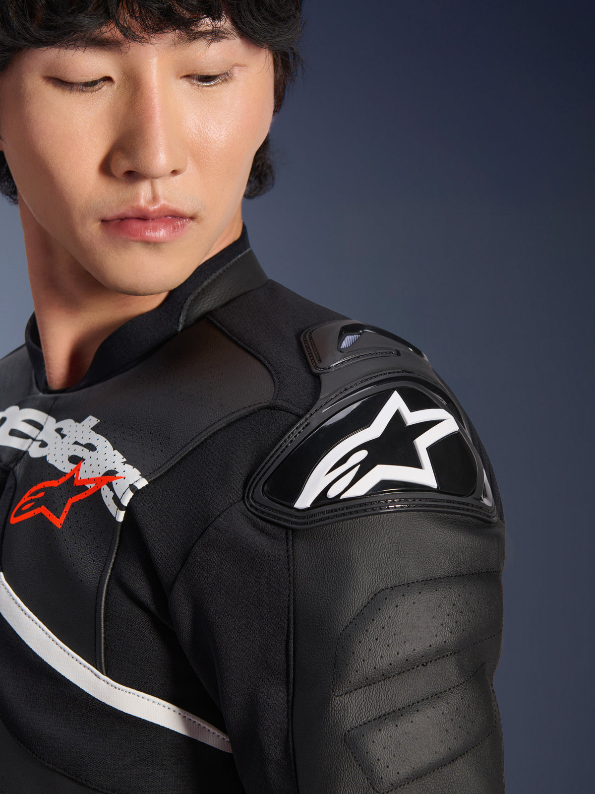 Nahaufnahme der Alpinestars Atem V5 Lederjacke in Schwarz-Weiß, mit dem DFS RR Schulterprotektor mit weißem Stern-Logo, perforierter Lederkonstruktion und rennsportinspirierten Brustgrafiken.
