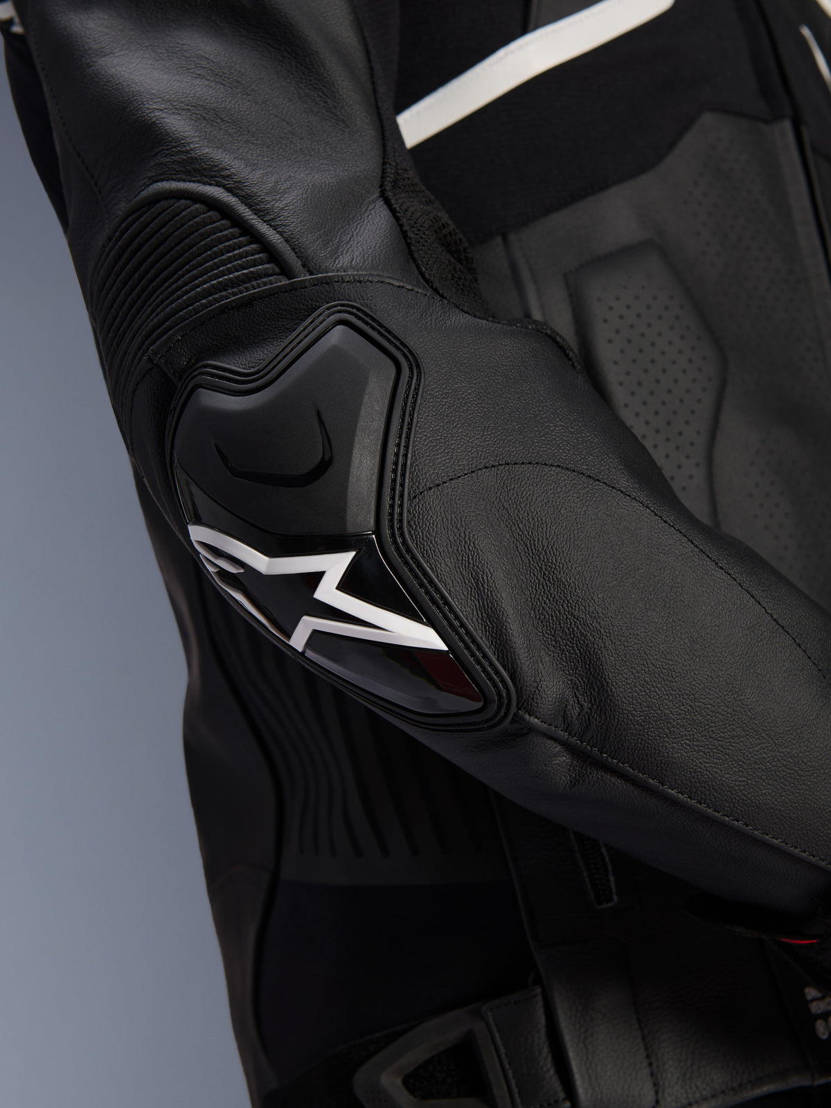 Alpinestars Atem V5 Lederjacke, Schwarz und Weiß, Nahaufnahme des DFS RR Ellbogenprotektors mit weißem Stern-Logo, mit Akkordeon-Leder und perforierten Texturen für sportliches Fahren