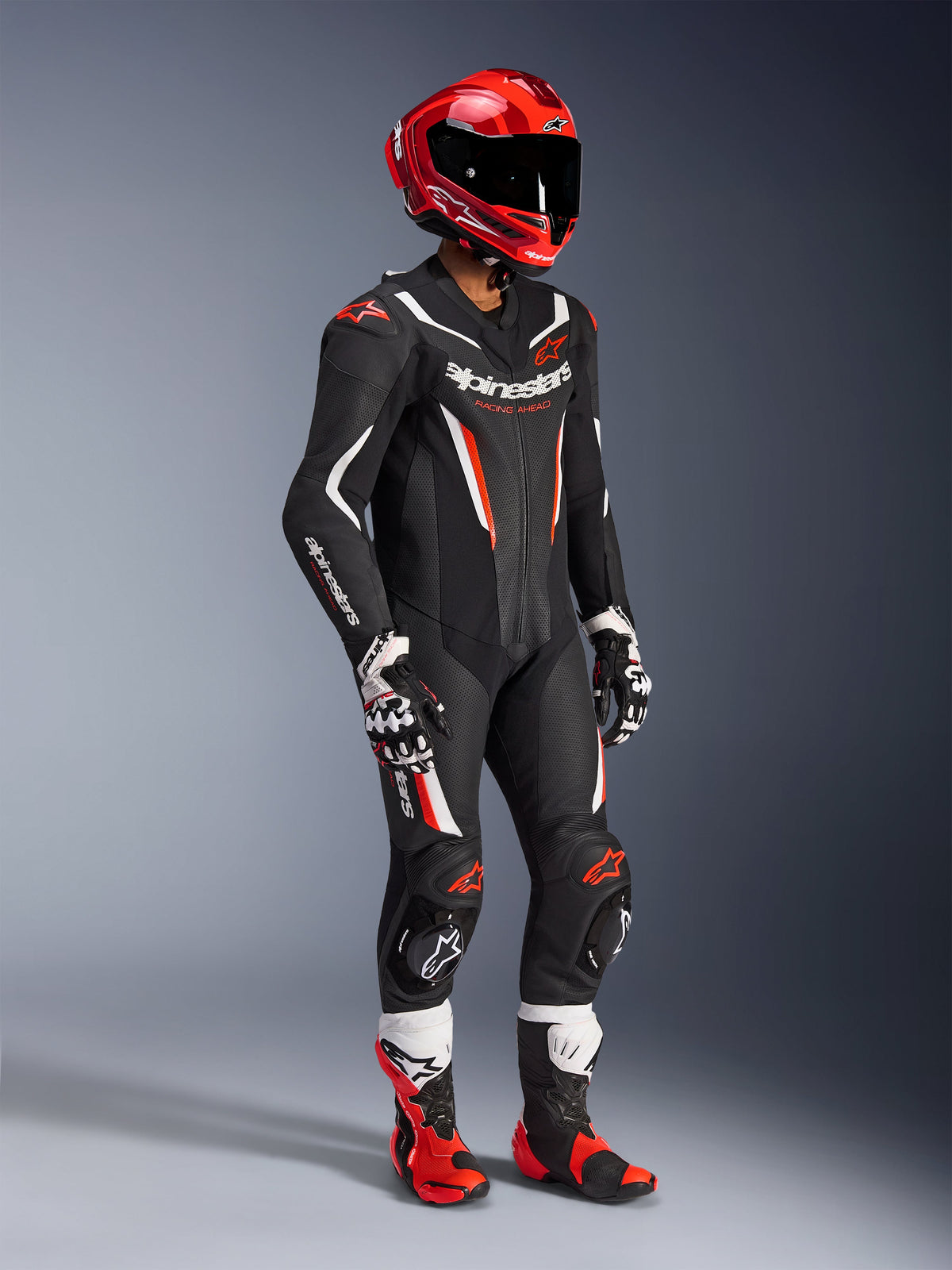 Alpinestars GP Force V2 Lederkombi – 1-Teiler, professioneller Rennanzug in Schwarz, Weiß und Fluo-Rot, mit perforierten Lederbahnen und DFS Lite Schilden. Komplettes Rennstrecken-Setup mit rotem Helm, passenden Handschuhen und Stiefeln.