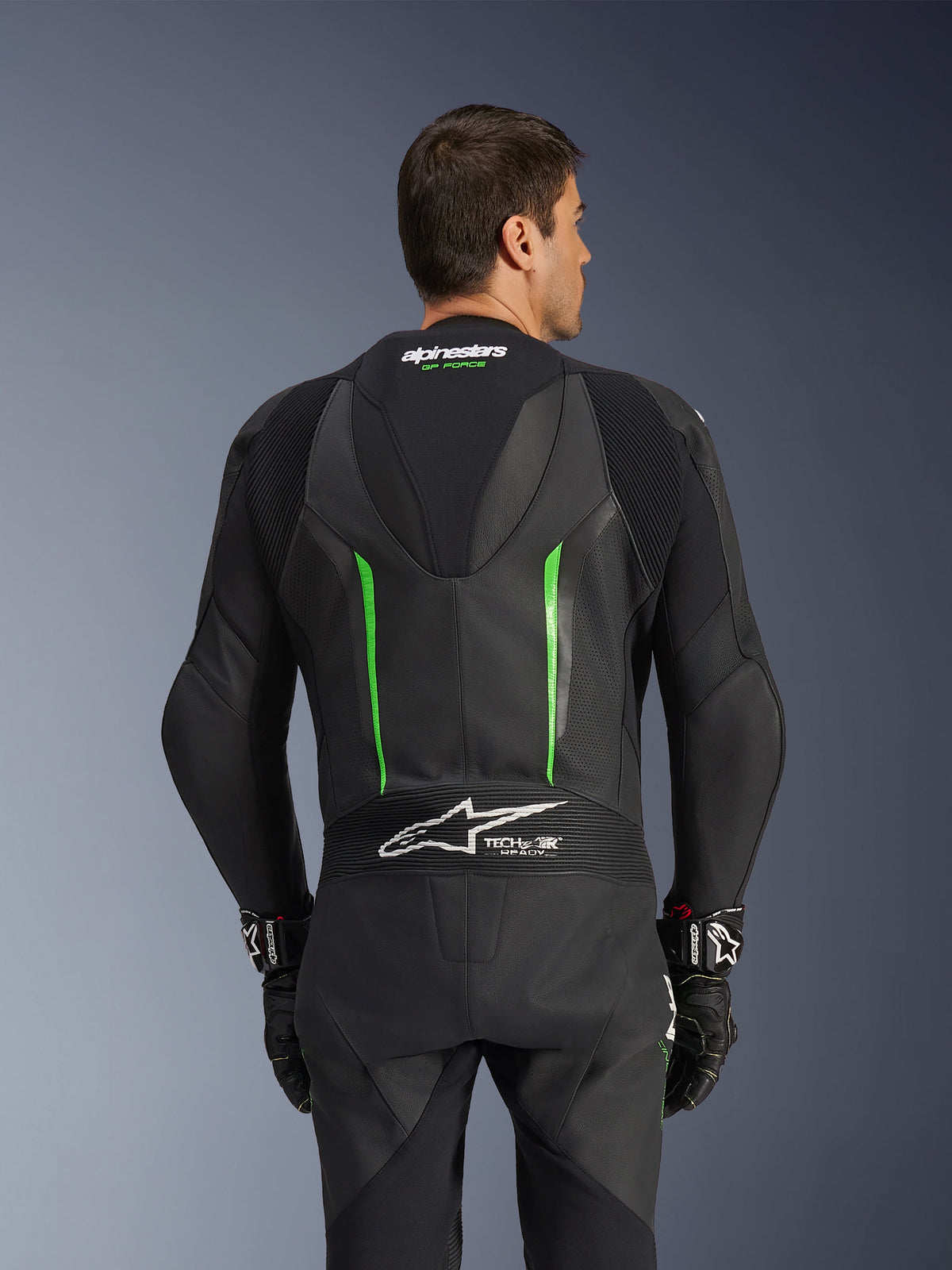 Alpinestars GP Force V2 Leather Suit - 1Piece, Black and Green, back view featuring aerodynamic speed hump, Tech-Air Ready branding, perforated leather zones, and accordion stretch panels for motorcycle racing