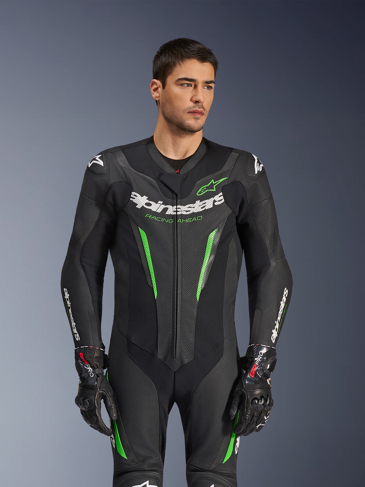 Alpinestars GP Force V2 Leather Suit - 1Piece, Black and Green motorcycle racing suit, worn by model, featuring perforated leather panels, bold white Alpinestars branding on chest and sleeves, and integrated shoulder protection for track performance.