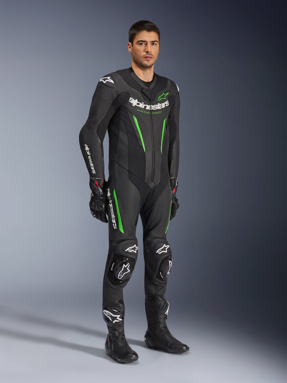 Alpinestars GP Force V2 Leather Suit 1-Piece, Black and Green, full racing gear worn with black gloves and boots, featuring perforated leather panels, white Alpinestars branding, and integrated knee sliders, professional track performance suit