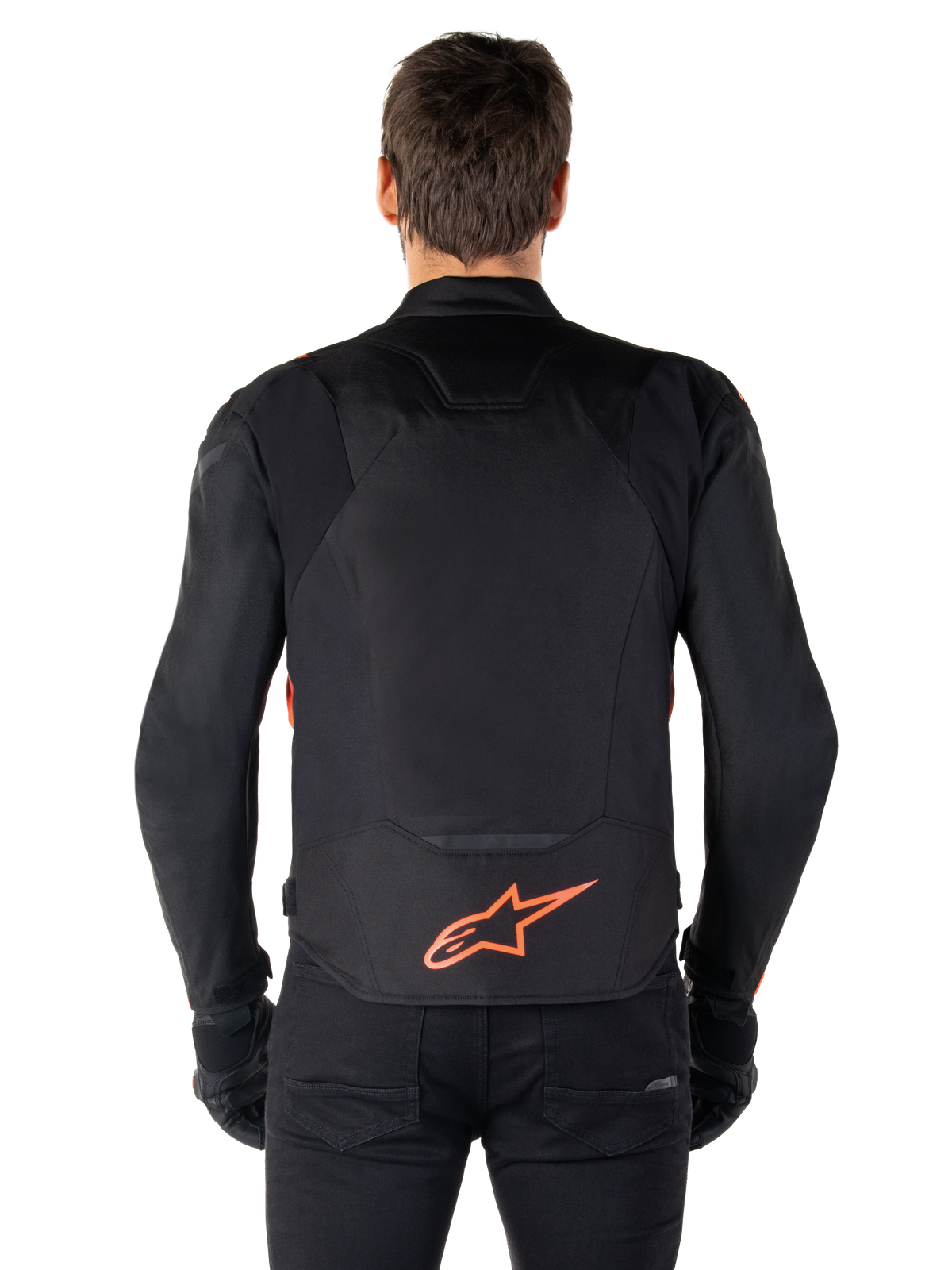 Alpinestars T-Jaws V4 Wasserdichte Jacke, Rückansicht, Schwarz mit fluoreszierendem Rot, rotes Alpinestars-Logo am unteren Rücken, technische Textilkonstruktion, getragen mit schwarzer Hose und Handschuhen für einen sportlichen Riding-Look