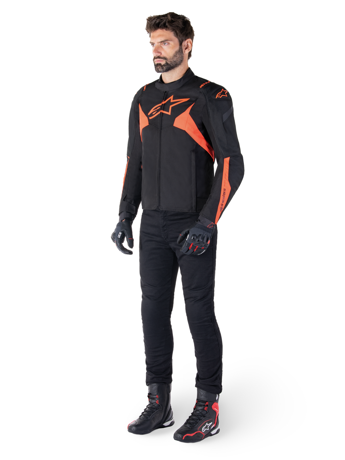 Alpinestars T-Jaws V4 Wasserdichte Jacke, Schwarz und Rot Fluo, getragen von einem männlichen Model mit schwarzer Hose, Handschuhen und Stiefeln, mit leuchtend orangefarbenen Akzenten und dem Alpinestars-Logo, sportliches Design für das Motorradfahren
