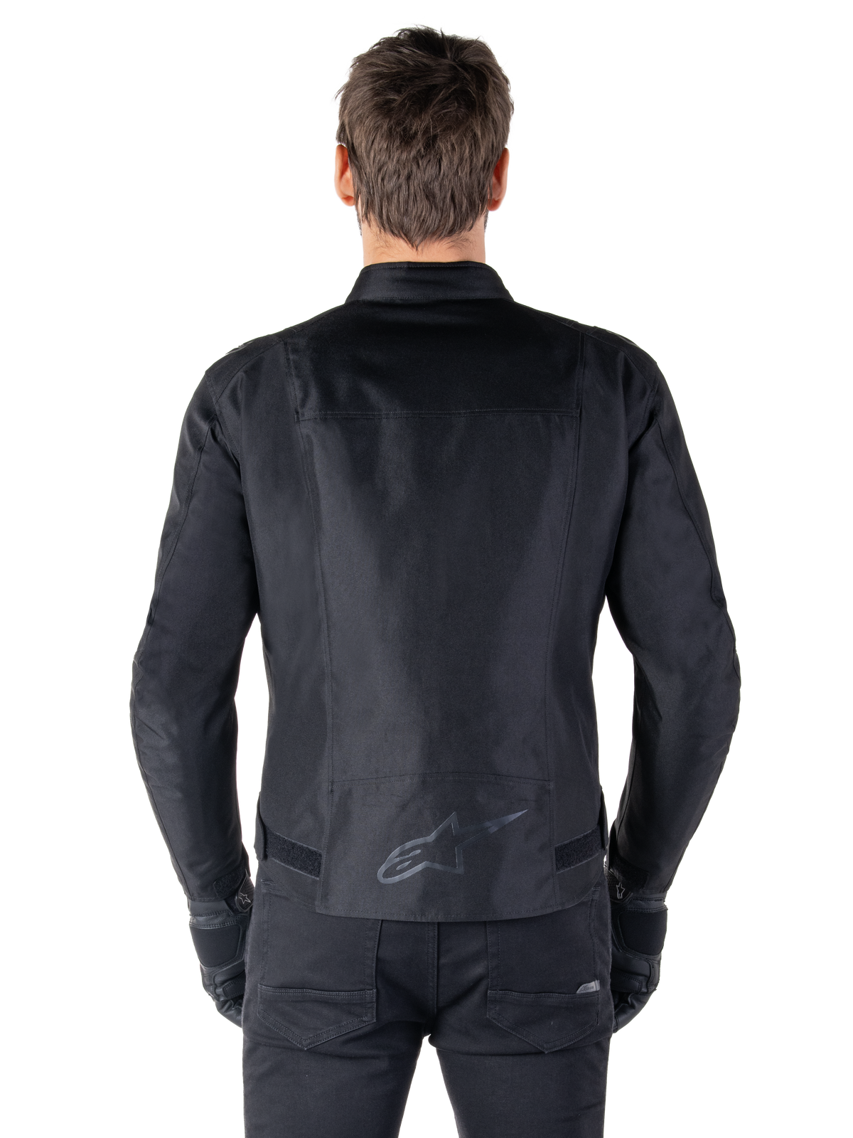 Alpinestars T-SPS V2 Wasserdichte Jacke, Schwarz, Rückansicht zeigt die sportliche Silhouette, reflektierendes Alpinestars-Logo am unteren Rücken und verlängerte Rückenpartie für zusätzliche Abdeckung beim Fahren.
