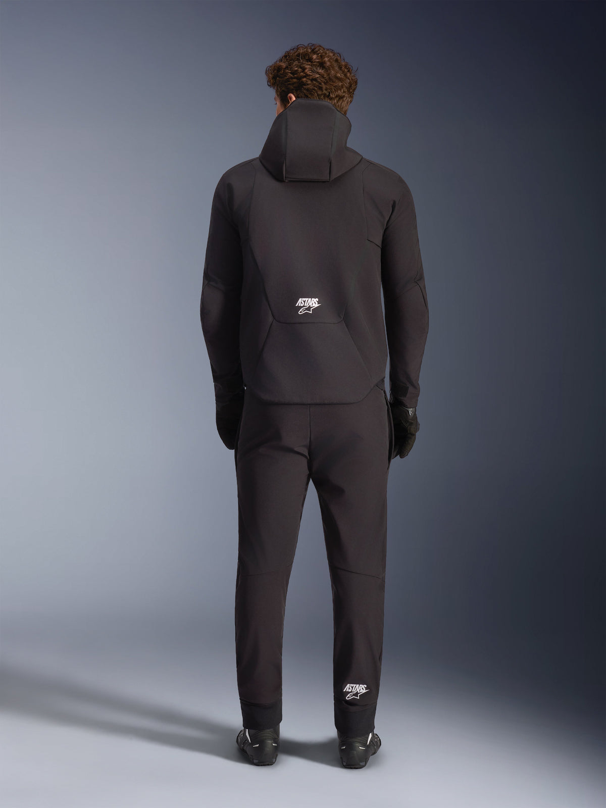Alpinestars Aeroshell Wasserdichte Jacke, schwarze Motorrad-Softshell-Kapuzenjacke, Herren, Rückansicht mit weißem ASTARS-Logo.