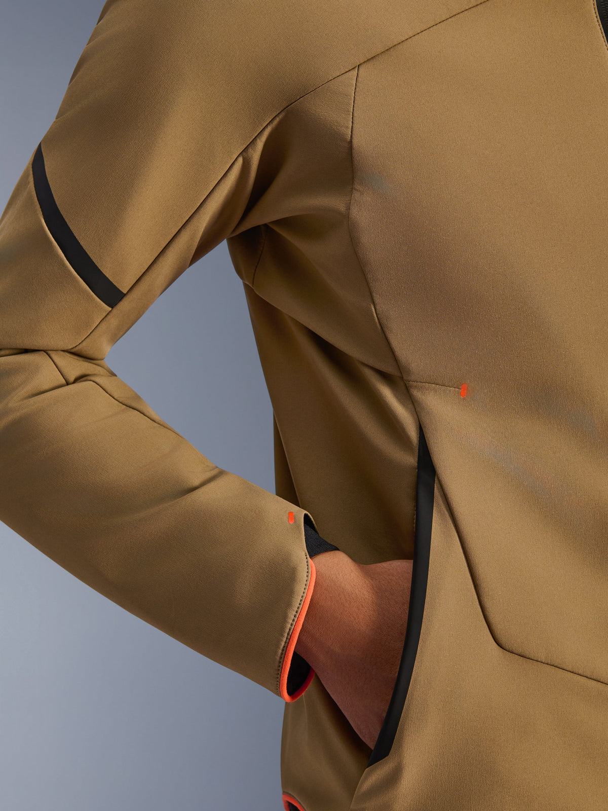 Nahaufnahme der Alpinestars Aeroshell Waterproof Jacke, Dunkelkhaki mit schwarzen und fluoreszierend orangen Akzenten, Detail der versteckten Reißverschlusstasche und des Ärmelbündchens, elastisches Softshell-Gewebe für das Motorradfahren