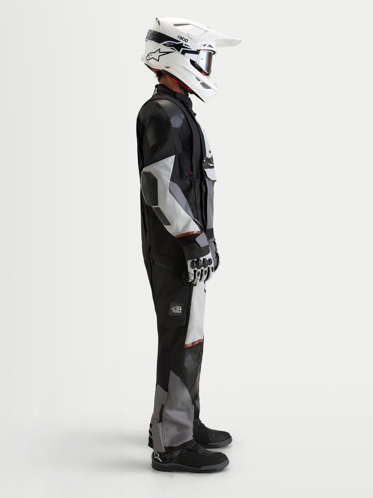 Alpinestars Harok V 2 Drystar Jacke, Herren-Abenteuer-Motorradjacke in Dunkelgrau, Eisgrau und Schwarz, getragen mit weißem Helm und Adventure-Ausrüstung im Studio