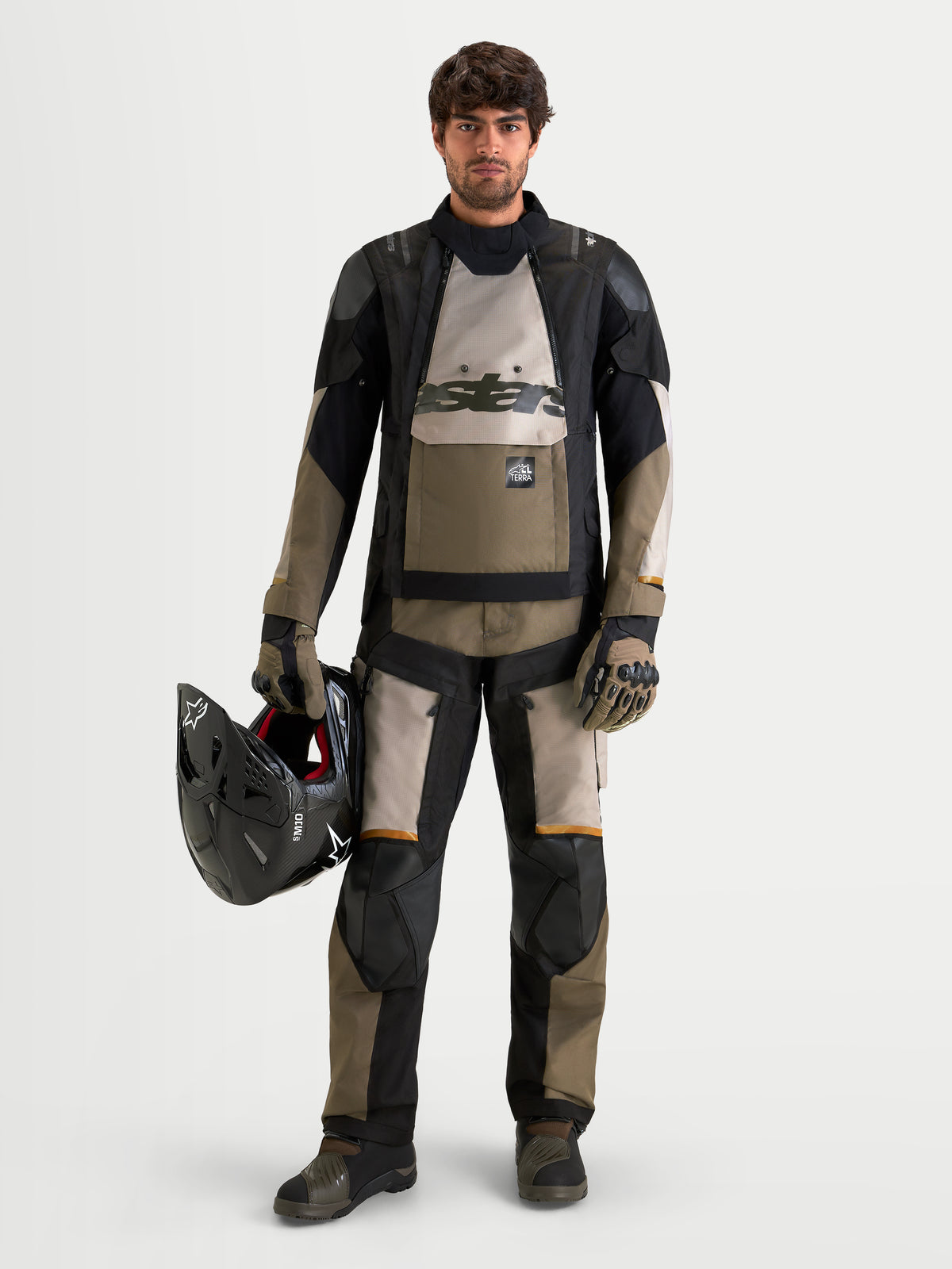 Alpinestars Harok V2 Drystar Jacket, men's all-terrain adventure motorcycle jacket in aluminum, walnut, and black, worn with matching adventure gear while holding a helmet