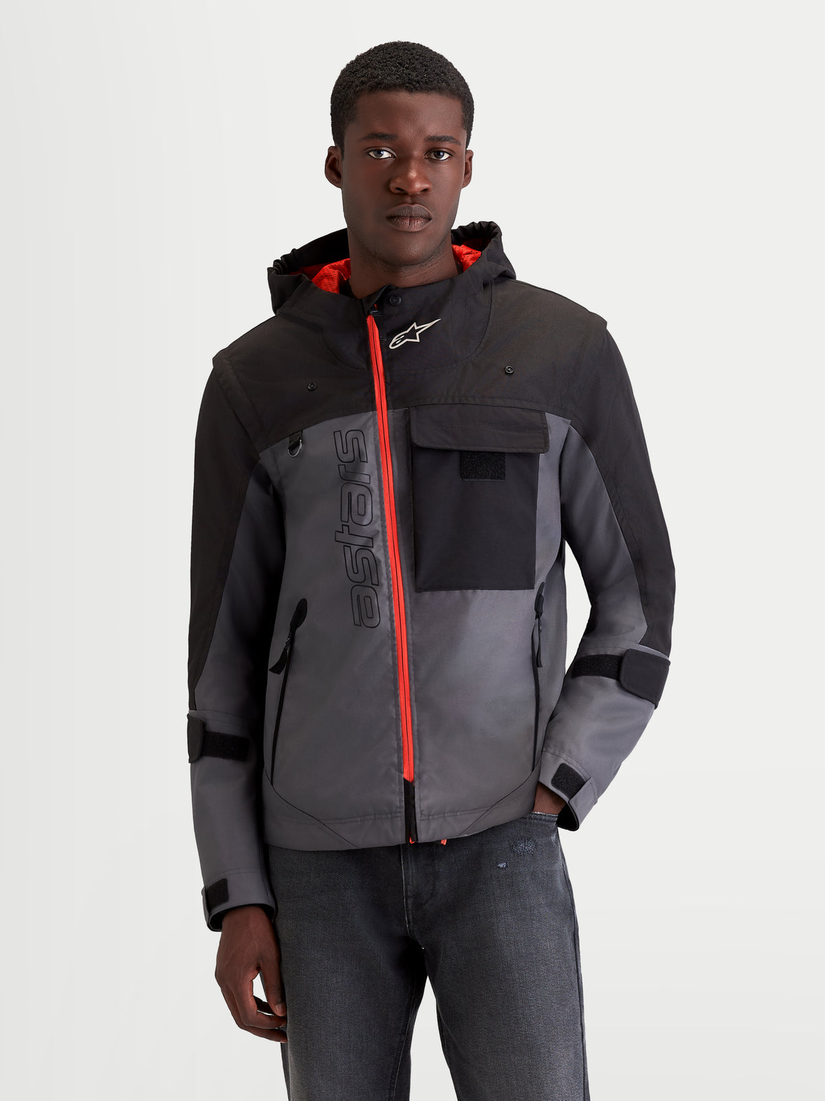 Alpinestars Morfex Parka WP Jacke, urbane Motorradjacke für Herren in Mondgrau und Schwarz, Vorderansicht am Model mit kontrastierendem orangefarbenem Frontreißverschluss und integrierter Kapuze