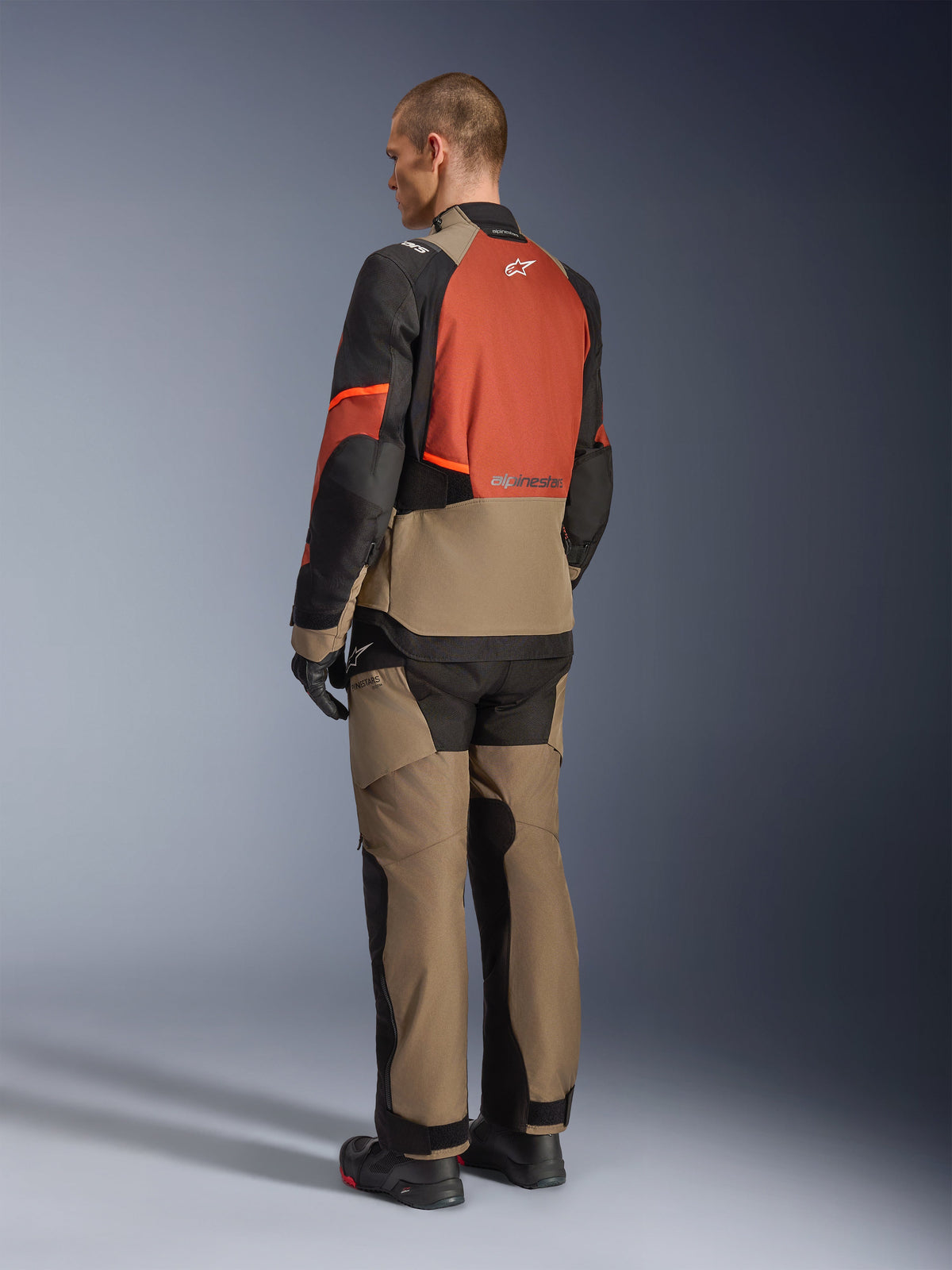Alpinestars Andes V4 Drystar® Jacket in Walnut Rust Black, model viewed from the back wearing matching textile pants, black gloves, and boots, featuring a technical multi-panel design for adventure touring and Alpinestars branding.