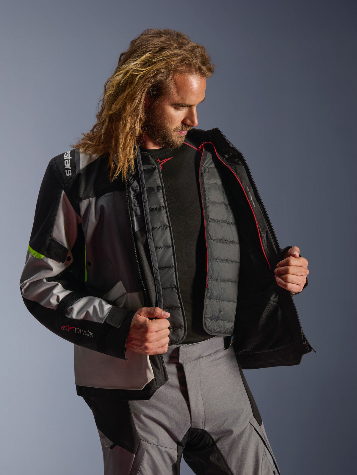 Alpinestars Andes V4 Drystar® Jacke, Adventure-Motorradausrüstung in Dunkelgrau, Eisgrau und Gelb Fluo, männliches Model zeigt das gesteppte Thermo-Innenfutter, getragen mit passender Motorradhose, Allwetter-Performance-Design