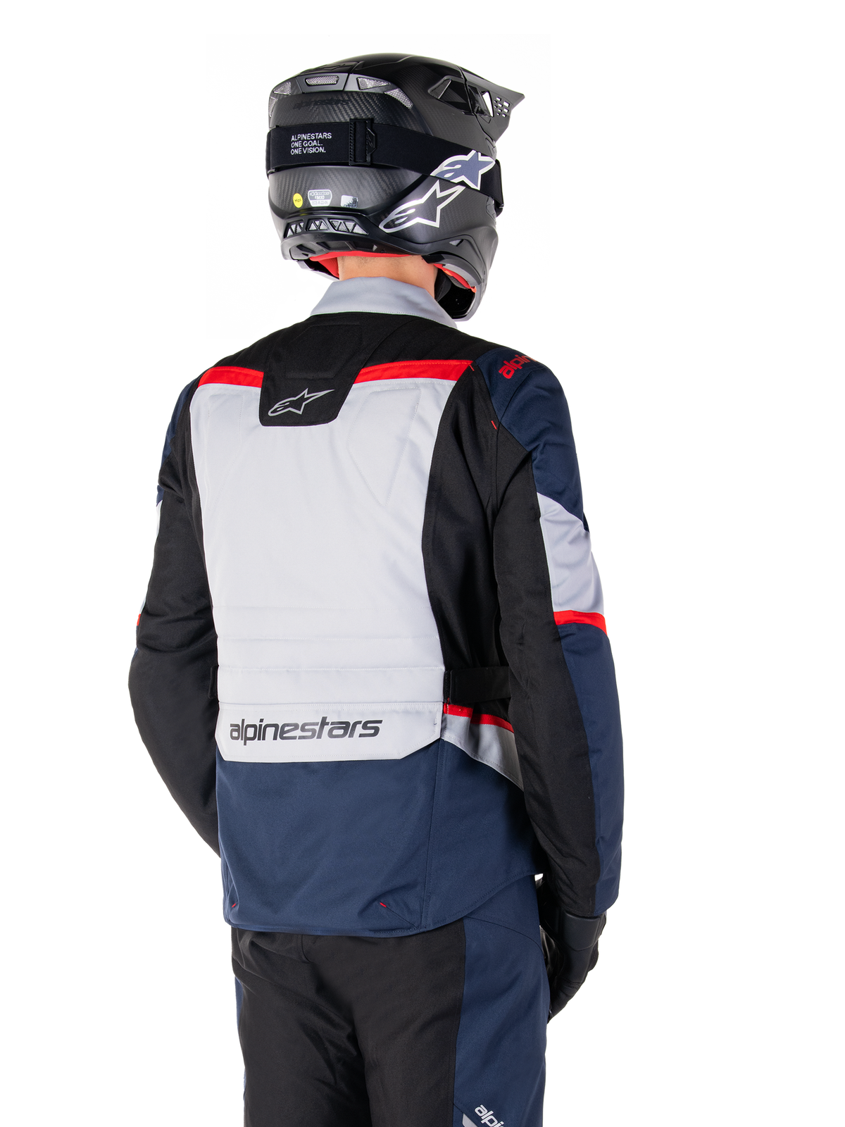 Alpinestars ST-1 wasserdichte Jacke, Dunkelblau, Schwarz und leuchtendes Rot, Rückansicht eines Fahrers mit schwarzem Adventure-Helm, mit hellgrauen Einsätzen und Alpinestars-Branding, Adventure-Touren-Motorradausrüstung