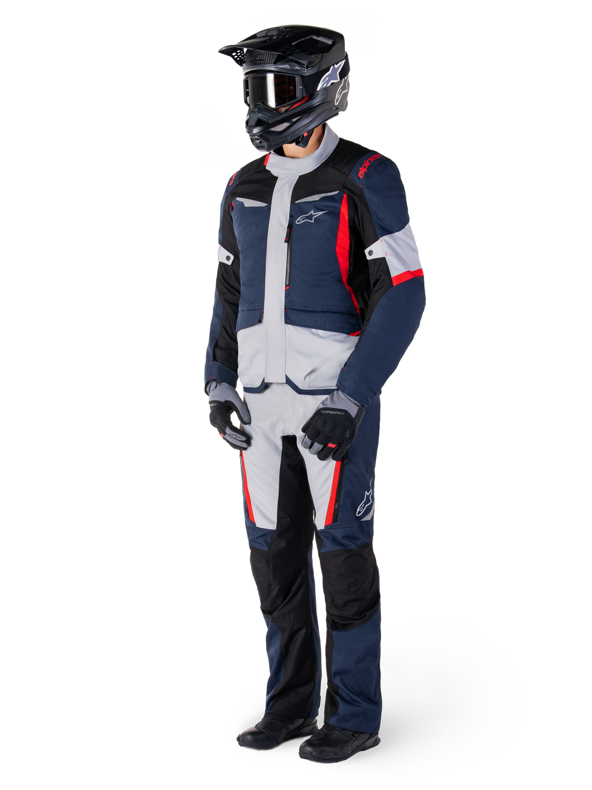 Alpinestars ST-1 Wasserdichte Jacke, Adventure-Tourenjacke, Dunkelblau, Schwarz und Hellrot, getragen von einem Fahrer mit passender Hose, schwarzem Adventure-Helm, Handschuhen und Stiefeln, mit grauen Einsätzen und roten Akzenten, stromlinienförmiges Adventure-Design mit Alpinestars-Logos