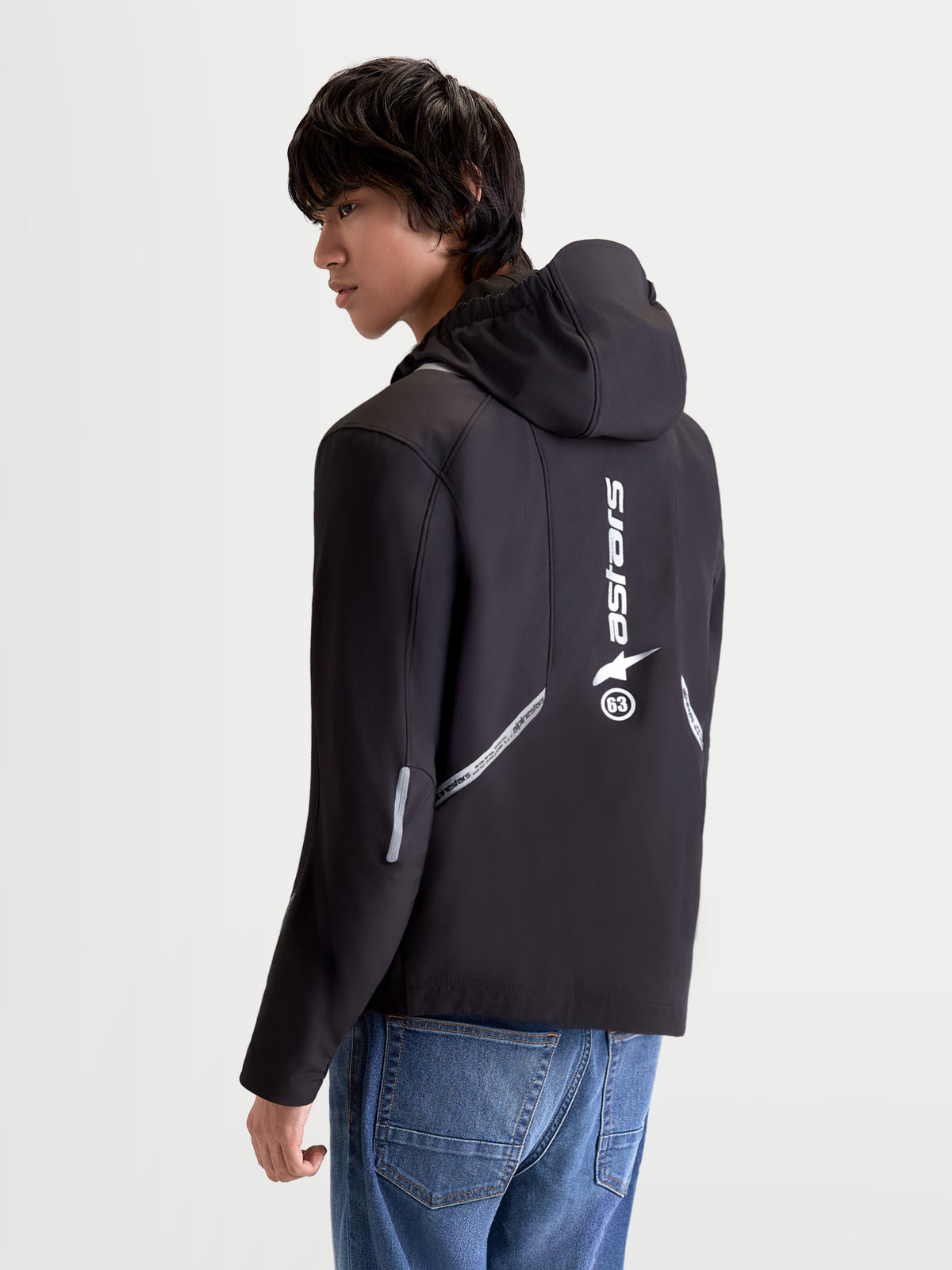 Alpinestars C-5 Drystar Jacket, men's urban contemporary motorcycle textile jacket in black, rear three-quarter view on a model showing integrated hood, reflective detailing, and vertical back logo print.