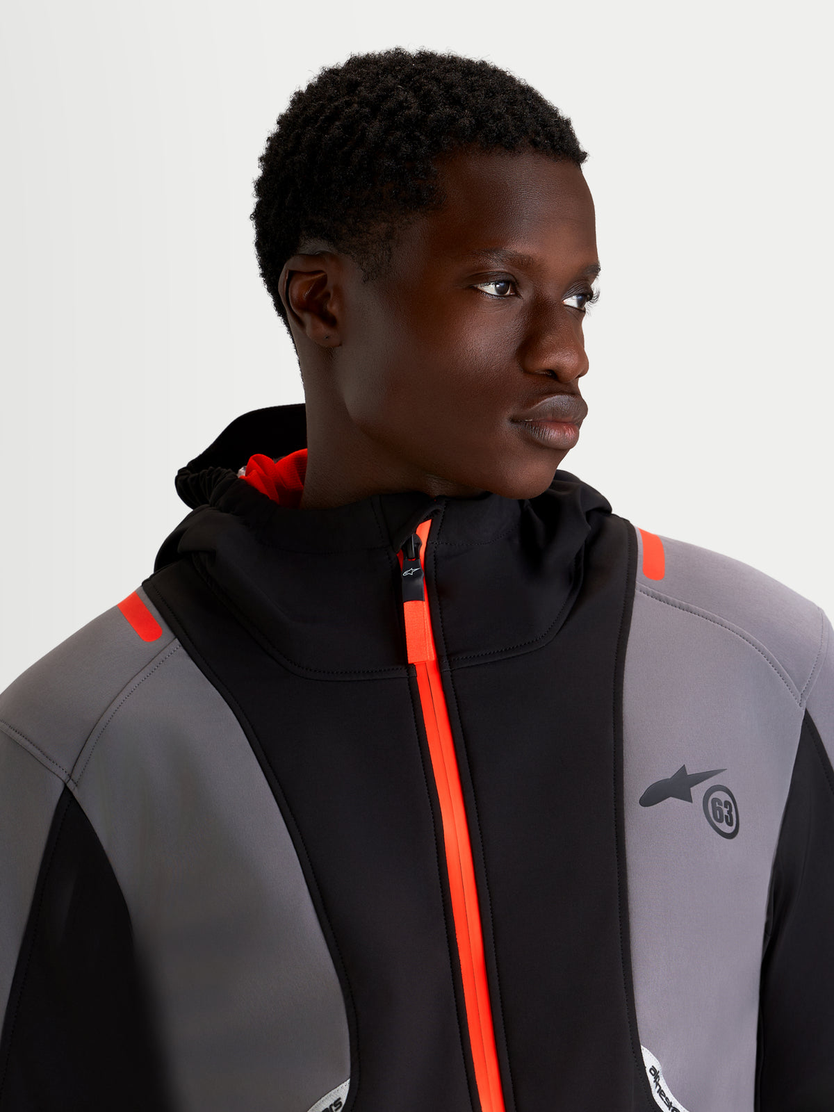 Alpinestars C-5 Drystar Jacket, men's urban motorcycle textile jacket in black and dark gray, close-up view on a model wearing the waterproof softshell jacket featuring a bright orange front zipper and integrated hood